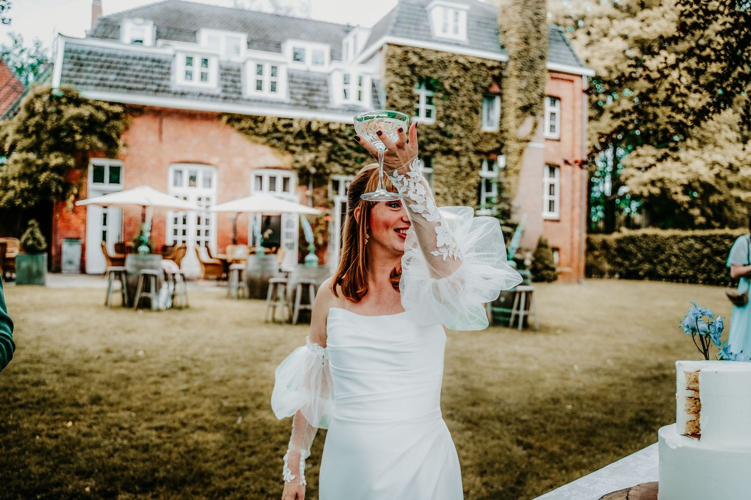 Wedding guests enjoying outdoor garden reception with rustic decor and string lights at elegant brick venue.