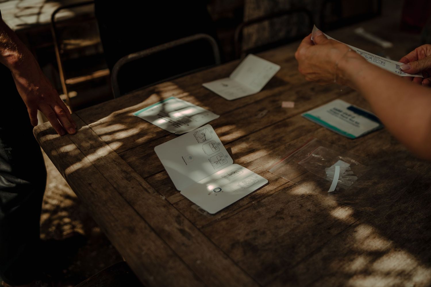 Sunlight casting dappled shadows across a wooden table with papers and cards.