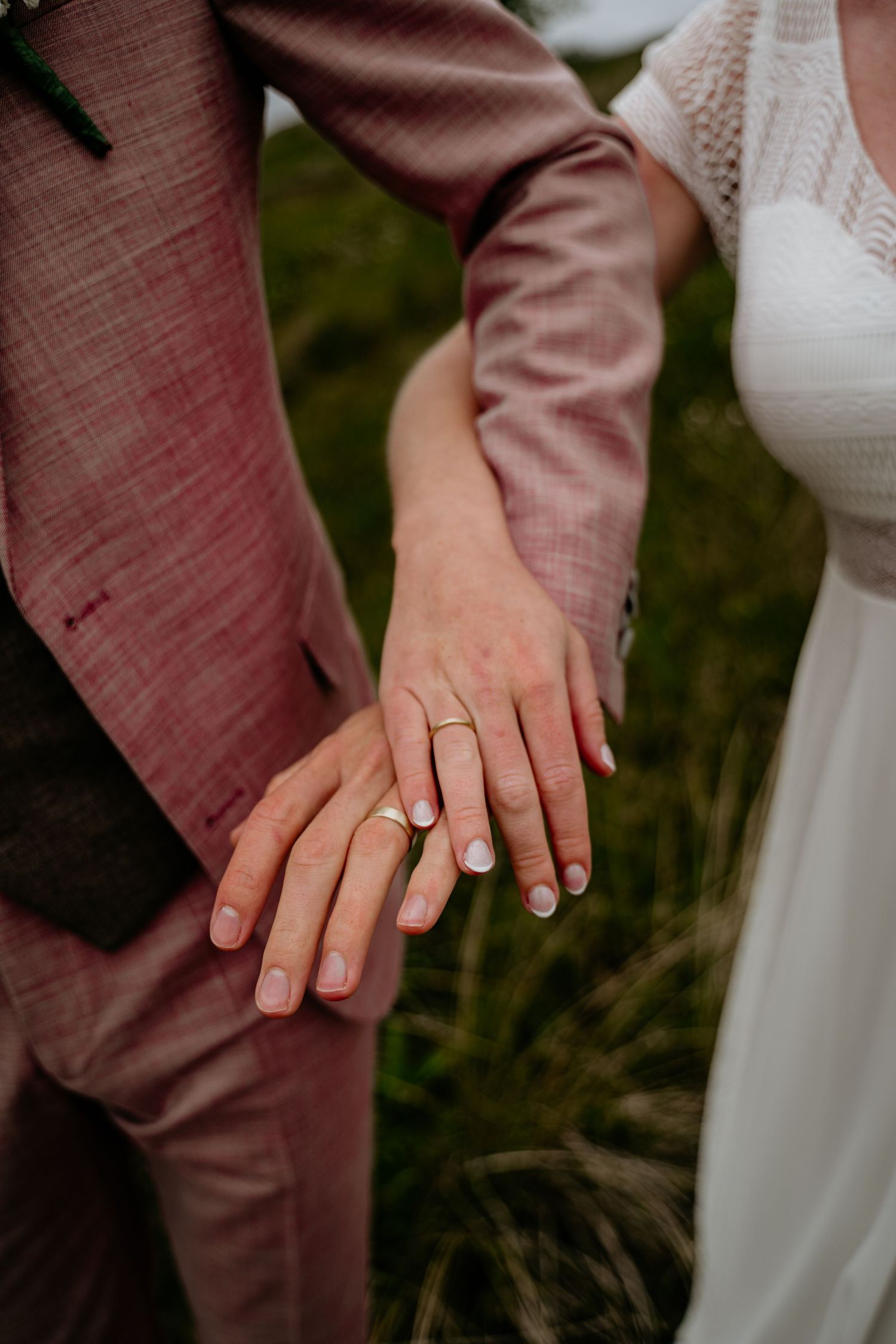 Close-up of hands wearing wedding rings against formal attire.