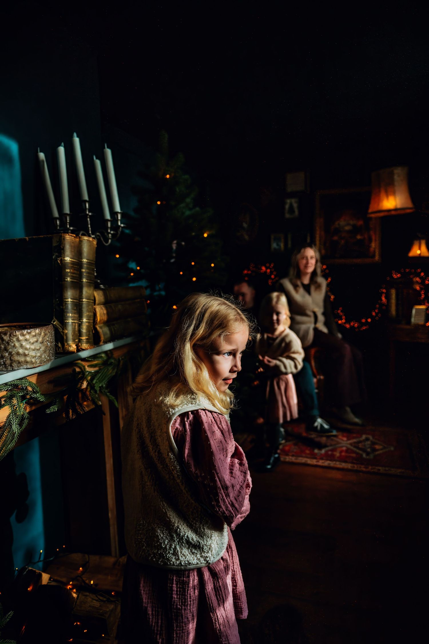 A series of dark moody photos showing a figure in a medieval style dress standing near candlesticks in dim lighting.