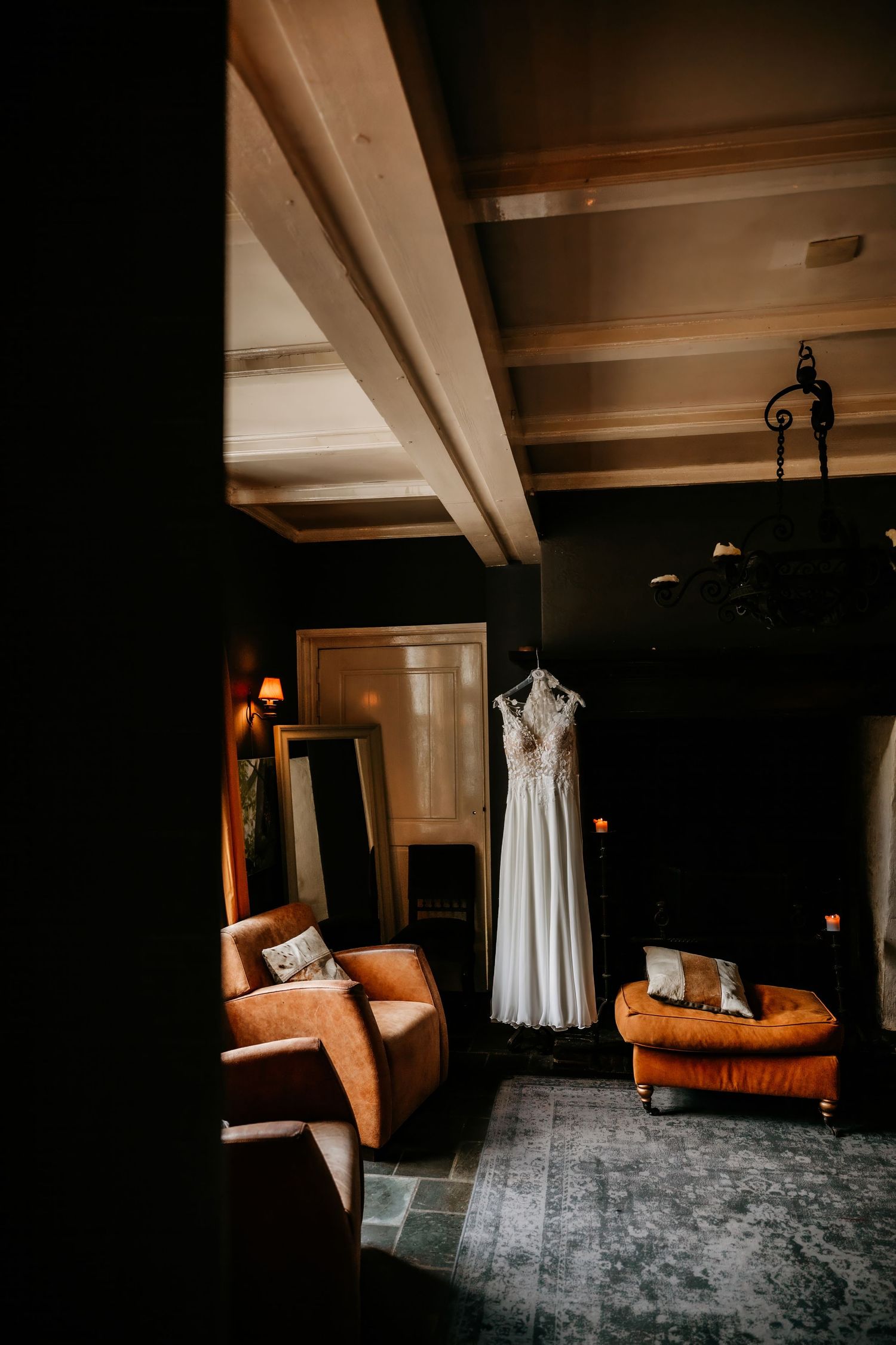 Elegant room interior with white dress displayed and leather furniture in warm lighting.