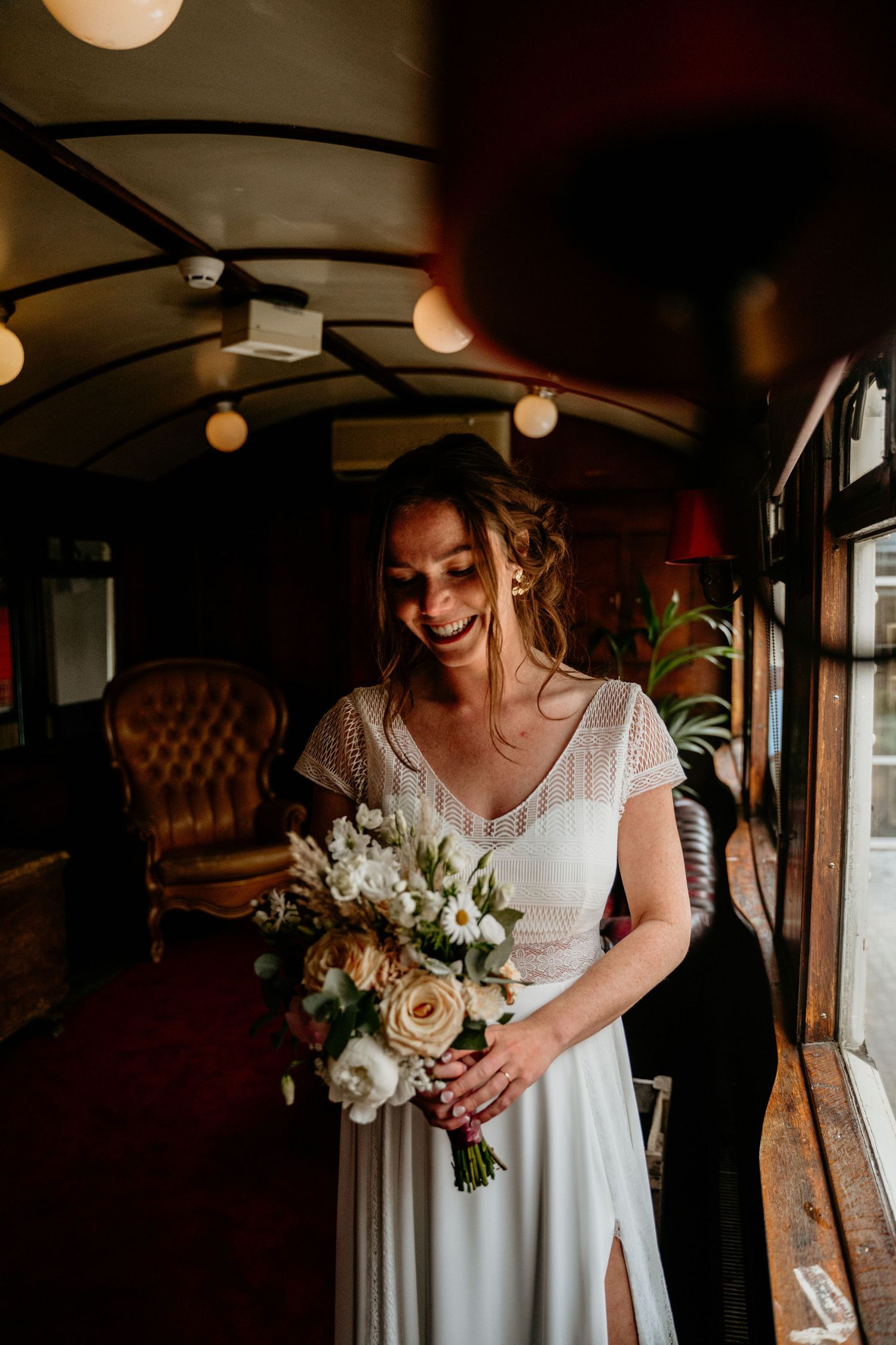 A person in a white wedding dress holds a beautiful bouquet of roses and flowers.