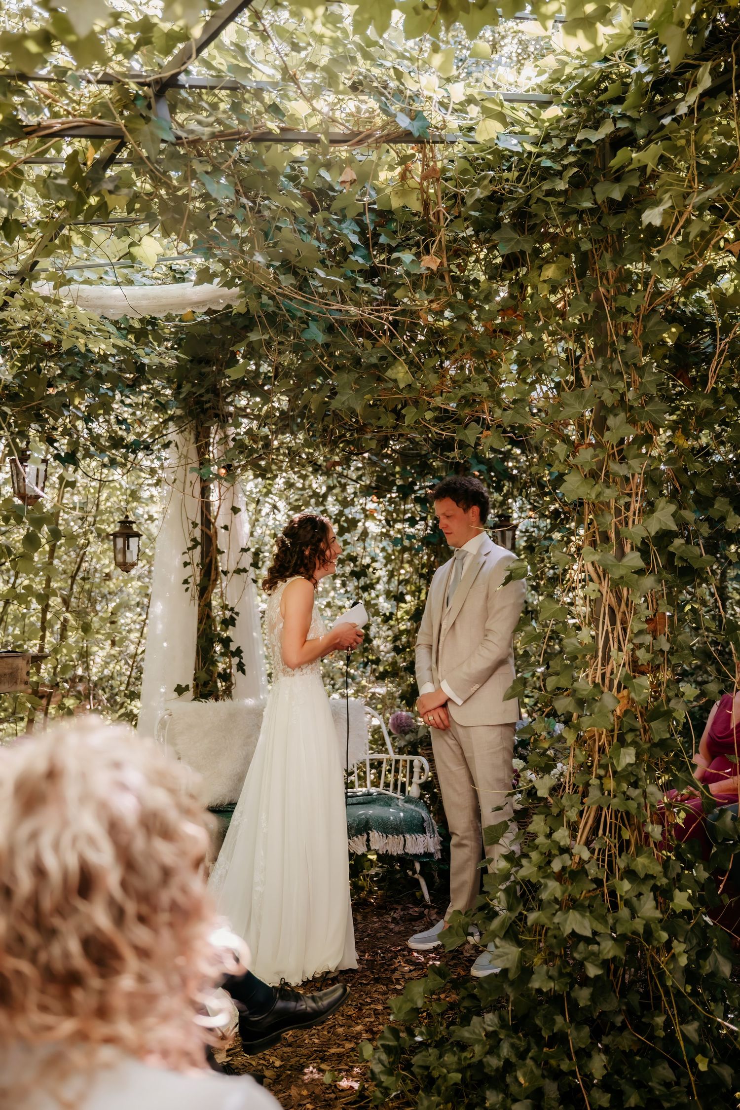 A romantic first look moment between a couple in a lush garden setting with ivy-covered walls.