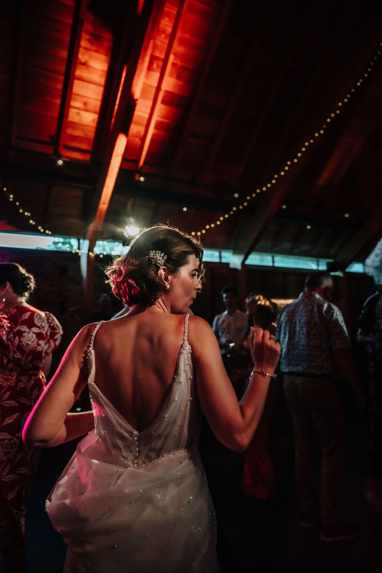 Dance party scene in a rustic barn with dramatic red lighting and string lights.
