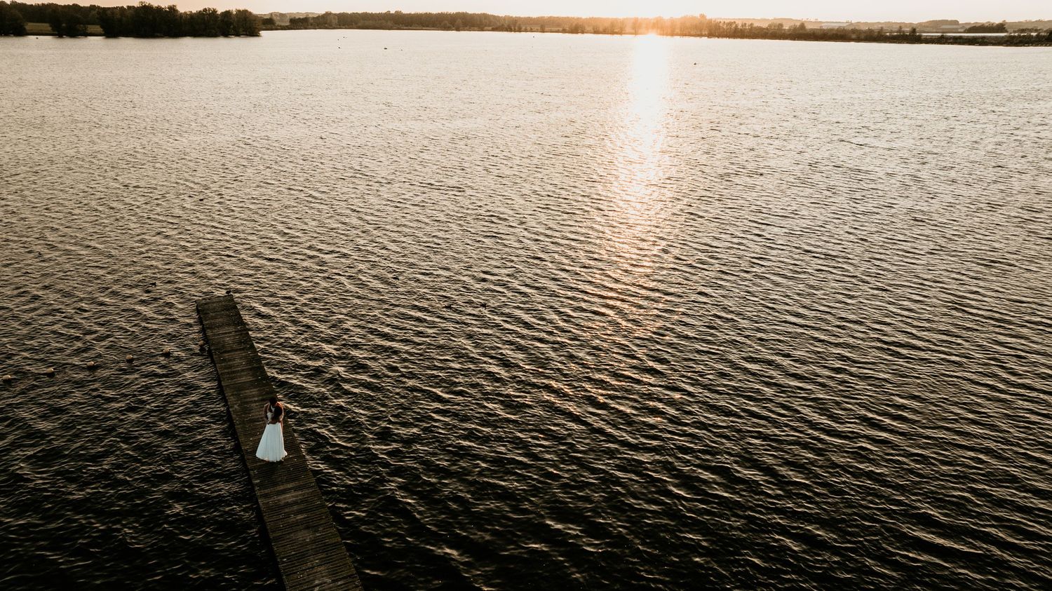 Panoramic sunset view over calm water with golden reflections.