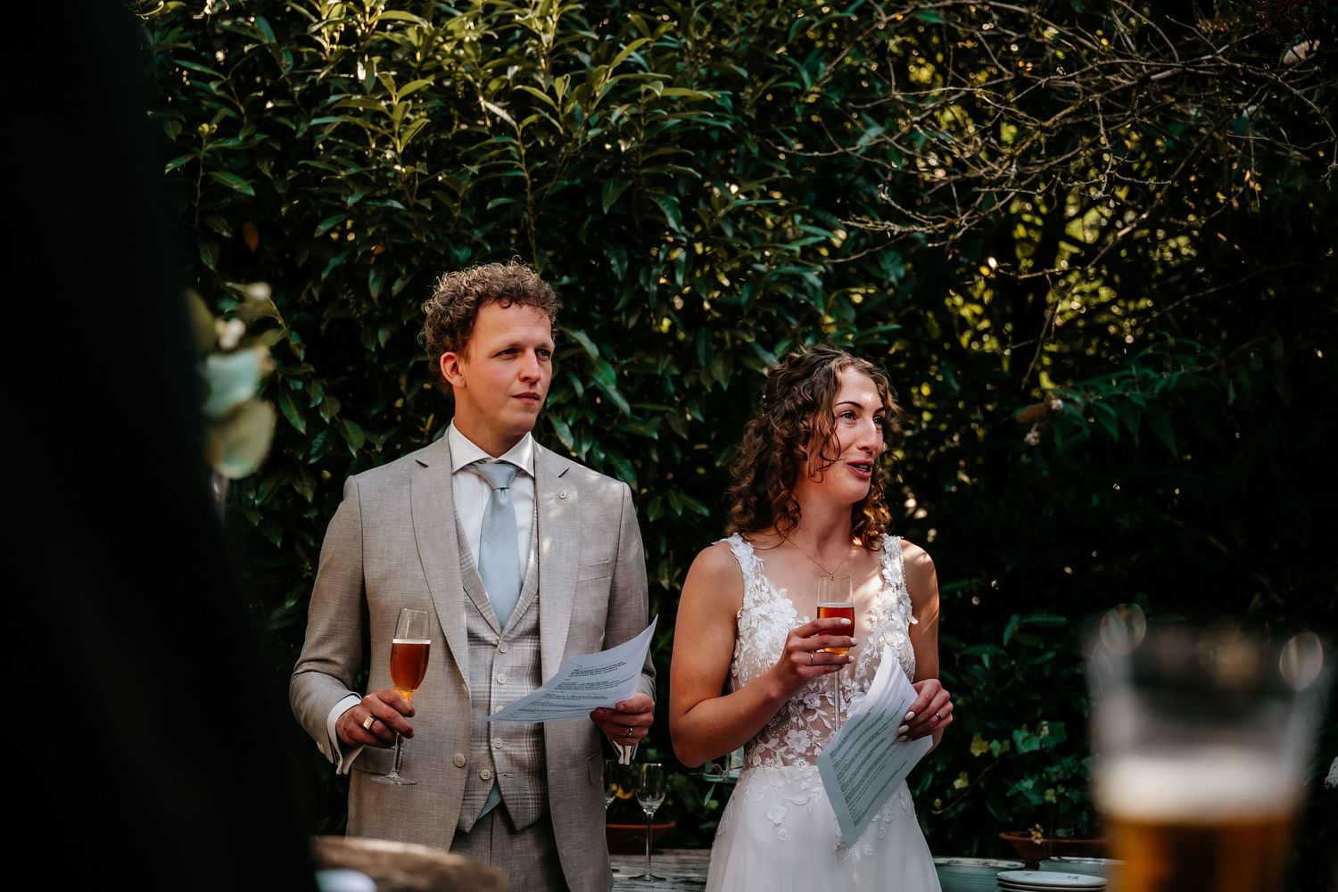 Newlyweds toast with drinks during their intimate garden wedding reception.