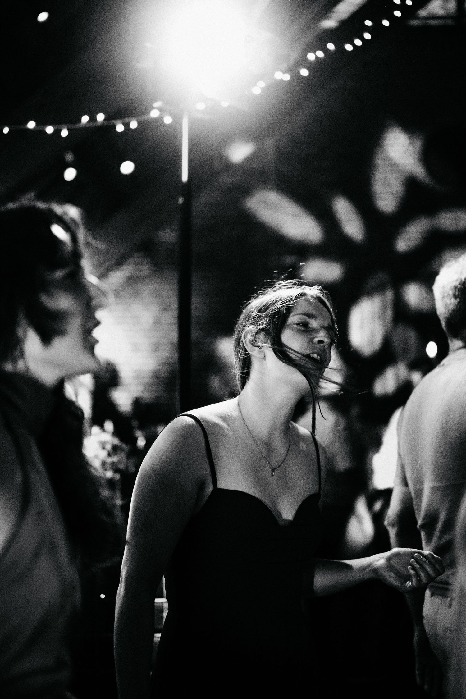 A black and white dance floor scene with silhouettes and twinkling lights in the background.