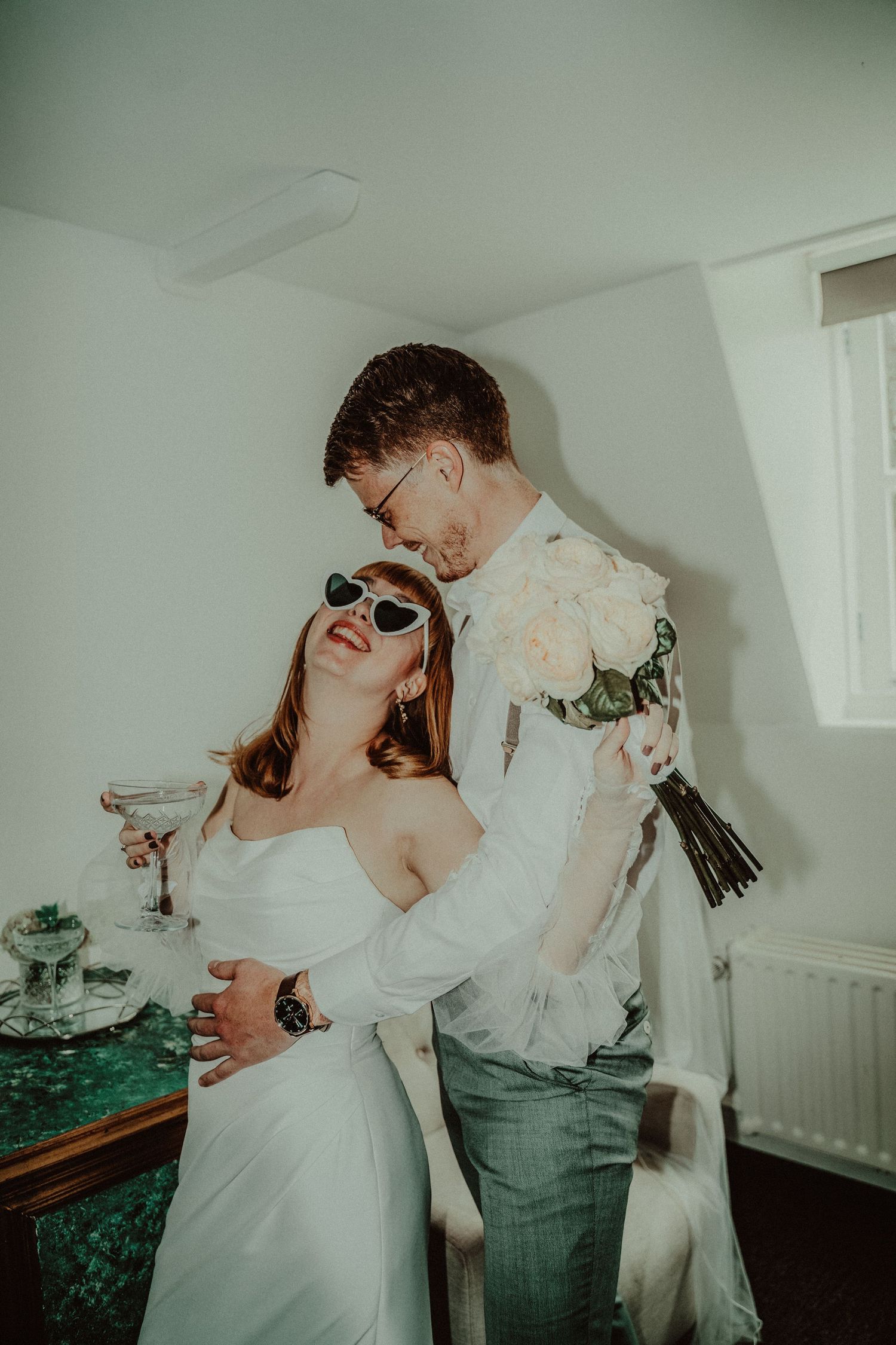 A couple shares a joyful moment with champagne glasses during their wedding celebration indoors.