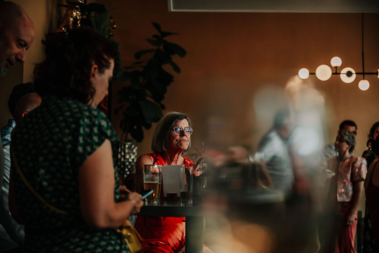 Soft-focus view of wedding reception guests mingling under warm lighting.