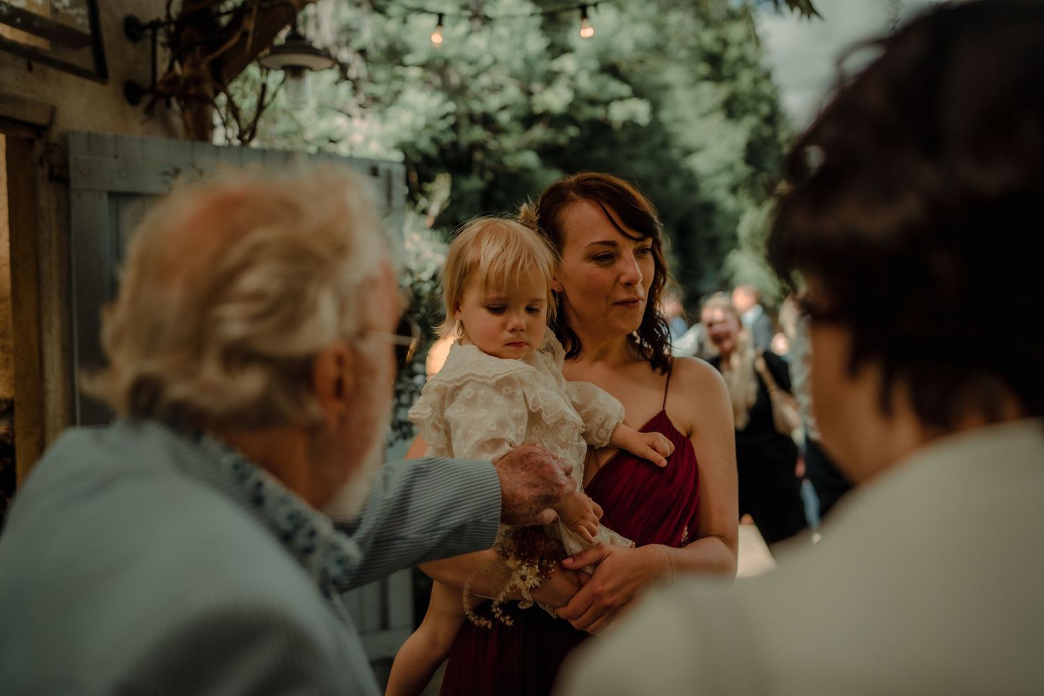 Outdoor wedding reception with guests enjoying drinks and conversation in a garden setting.