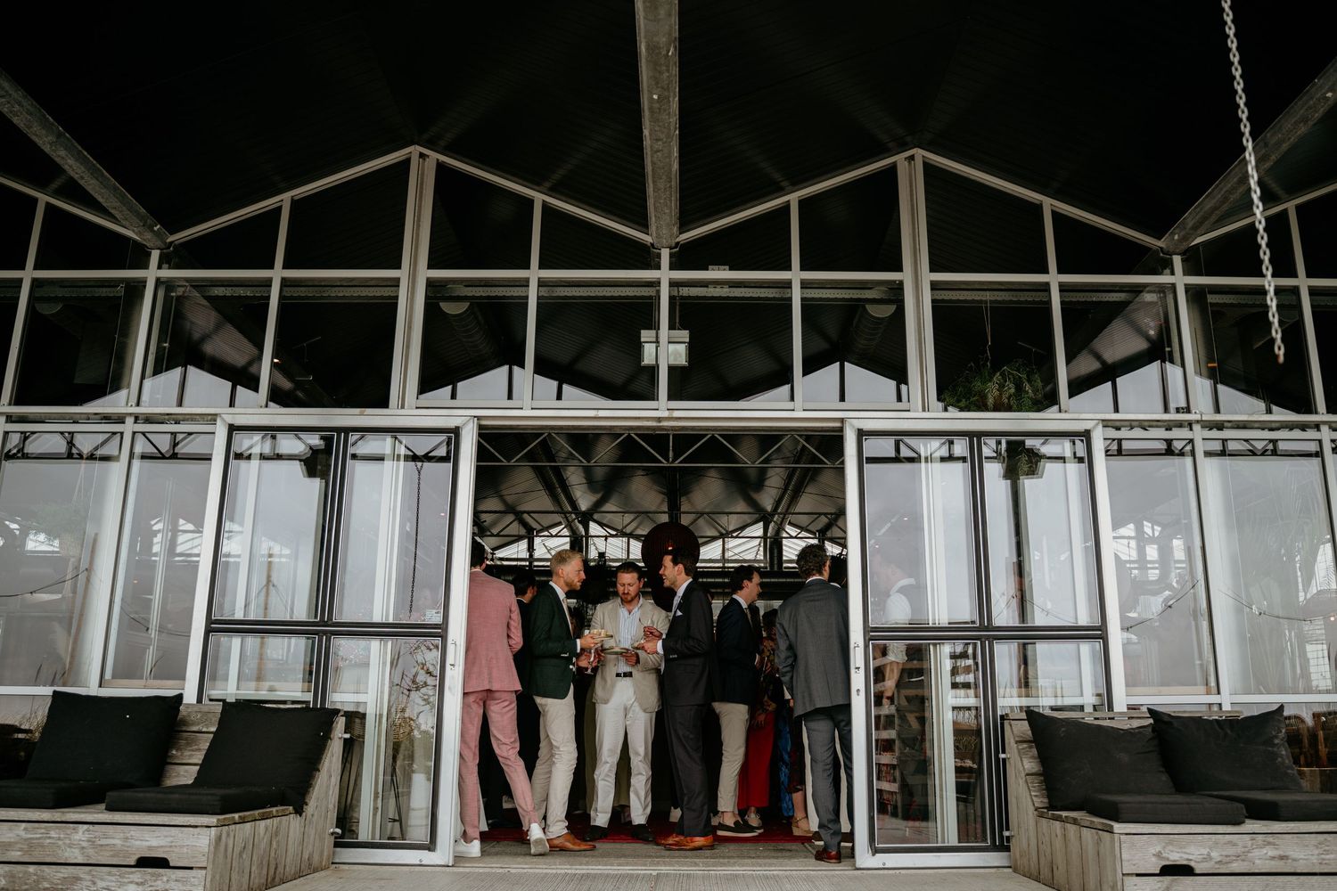 A group of people stand together in a modern glass building entrance at night.