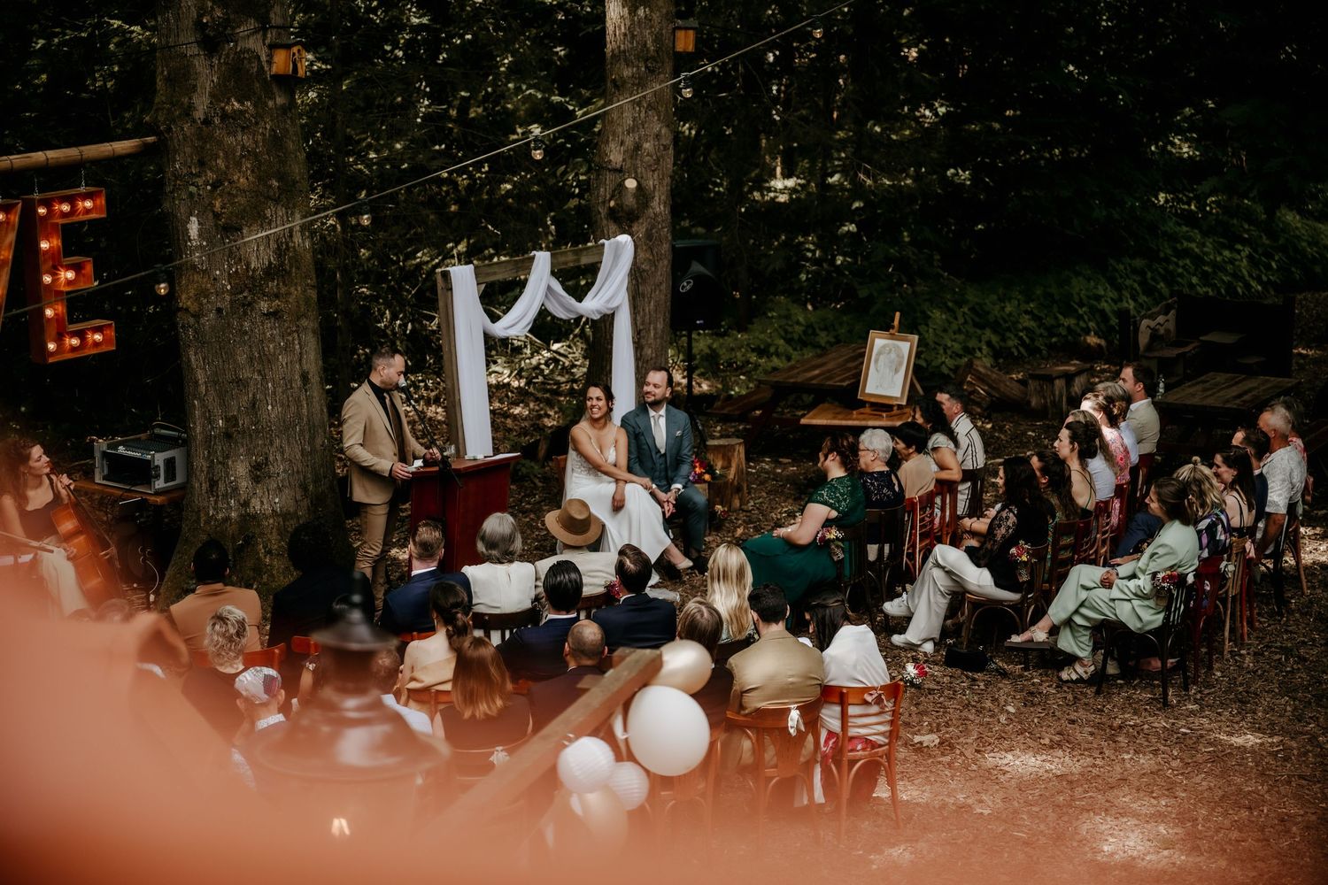 A nighttime outdoor gathering with white balloons and string lights illuminating a crowd of people.