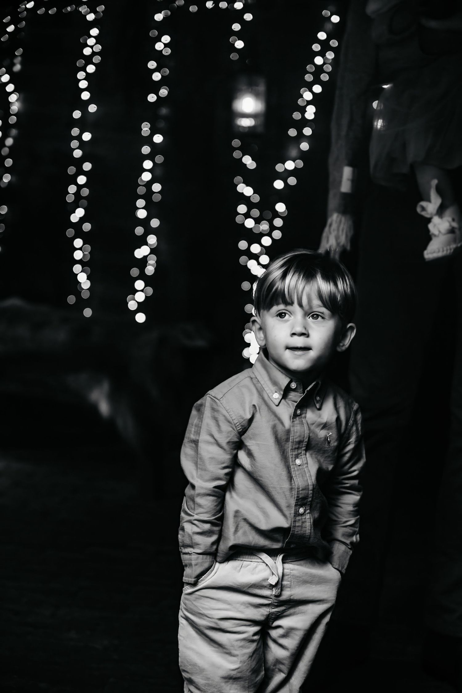 A child in a light-colored shirt plays against a dark background with twinkling lights.