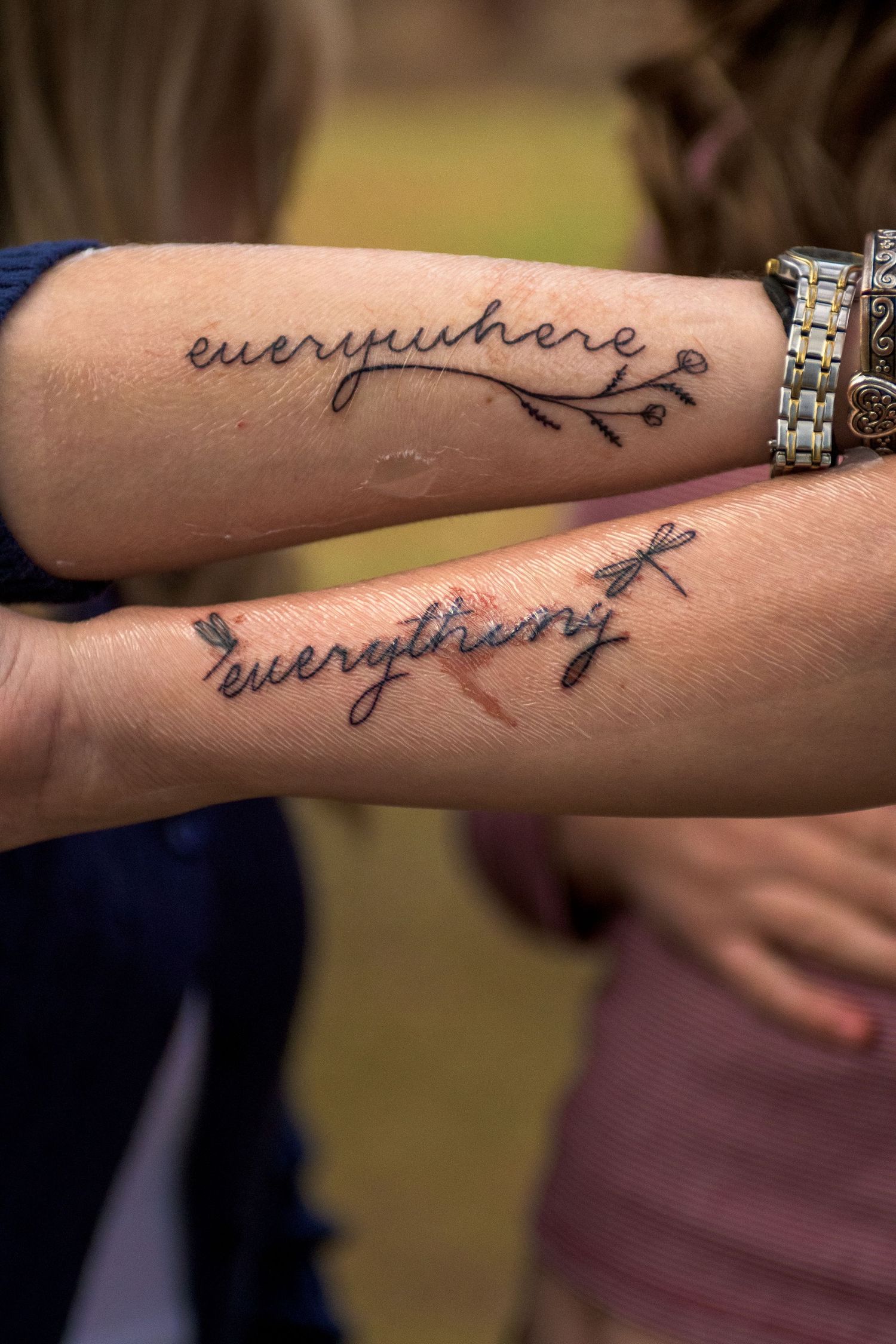 Two matching forearm tattoos reading 