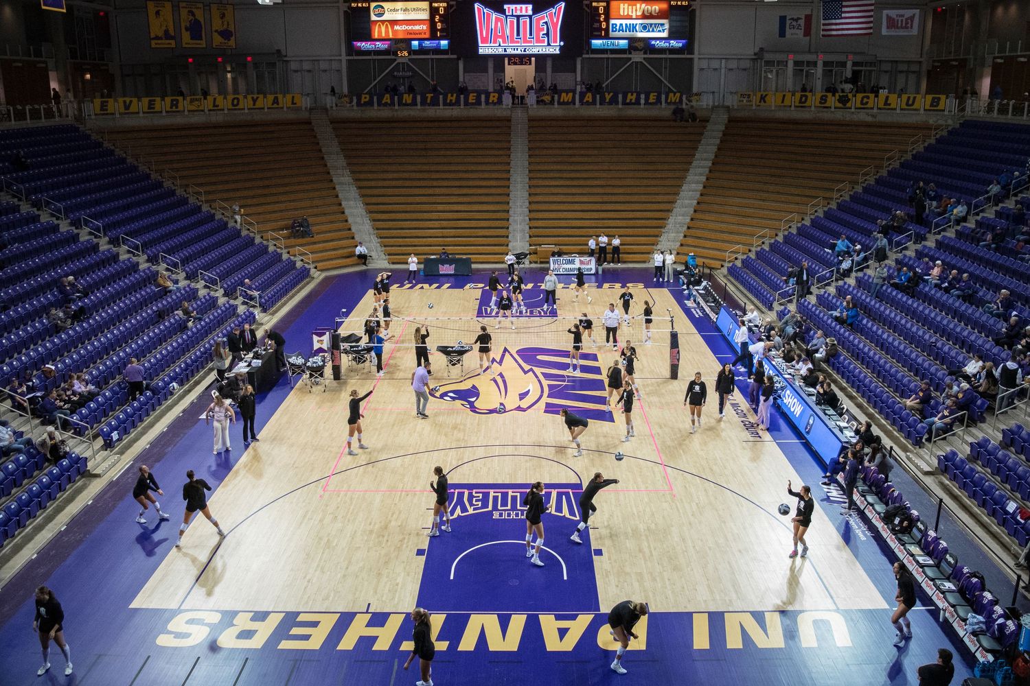 UNI Panthers basketball arena with players warming up on hardwood court, purple seats, and Missouri Valley Conference signage.