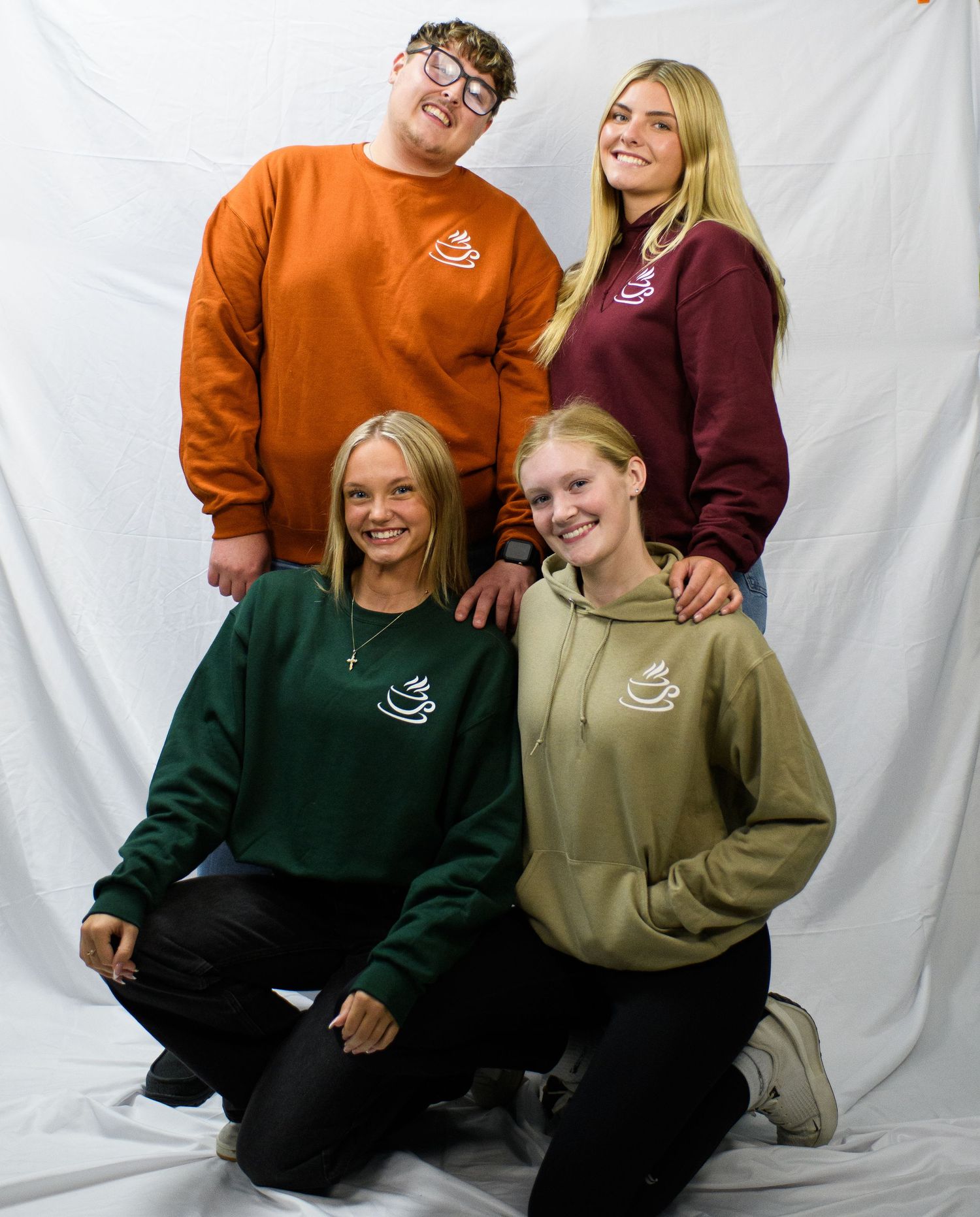 People wearing matching green and orange color block hoodies pose together against a white backdrop.