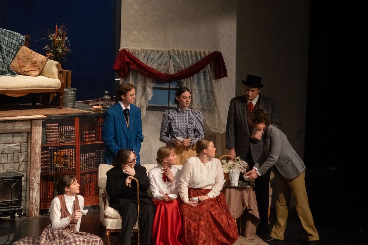Stage performers in period costumes act out a scene in what appears to be a Victorian-era theatrical production.