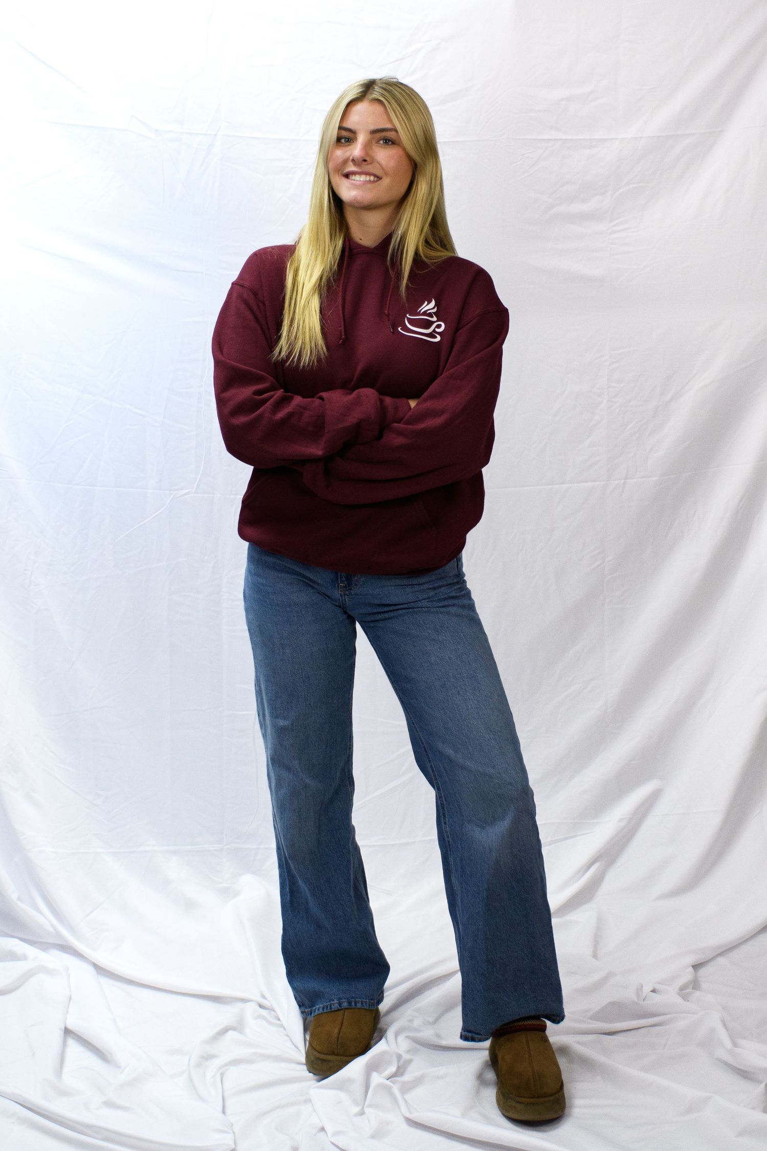 Person in burgundy sweatshirt and wide-leg jeans poses against white backdrop in three casual stances.