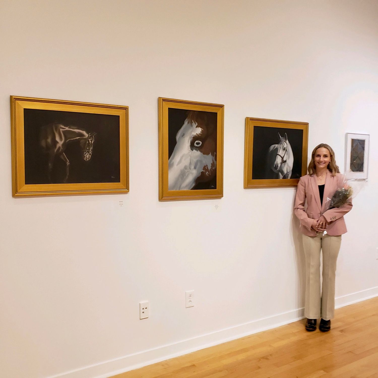Artist Olivia Blain with her oil paintings at a gallery exhibition