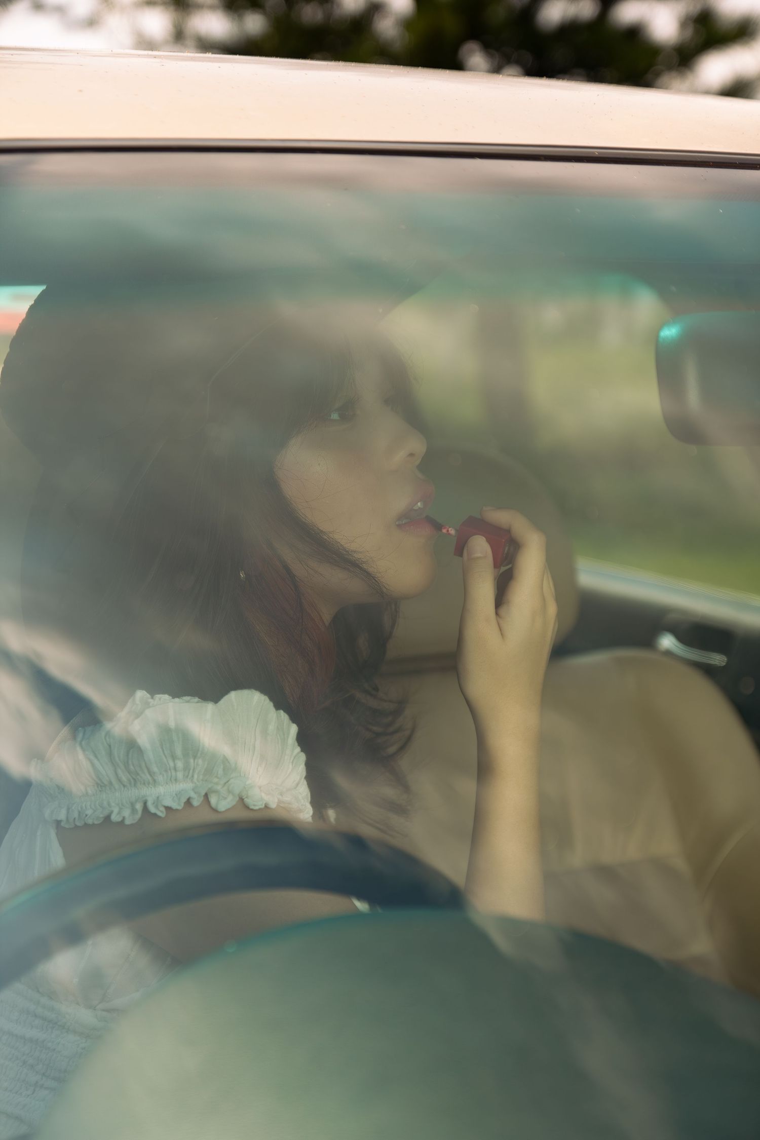 cowgirl applying lipstick using her car mirror