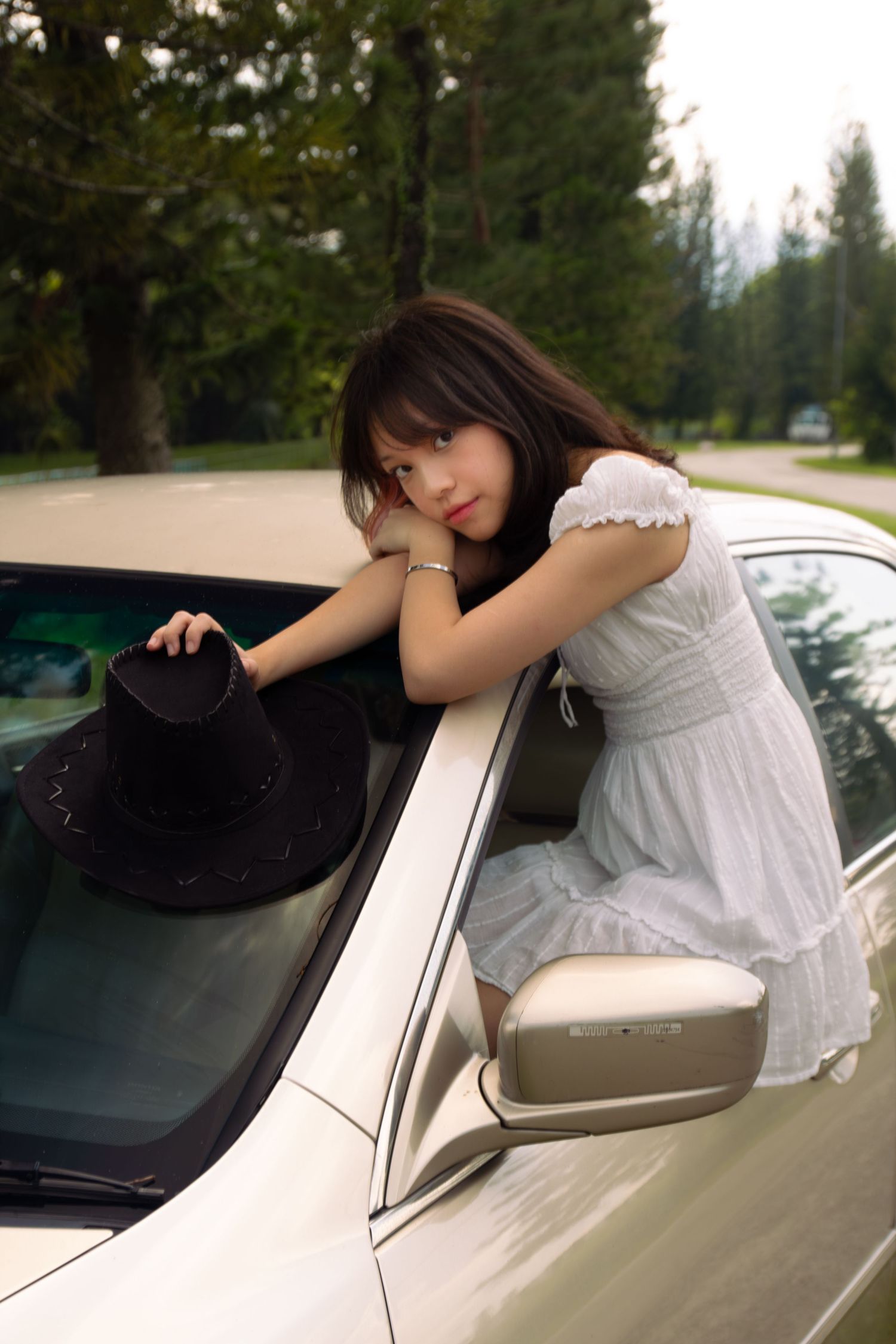 cowgirl with half her body out the window of her car