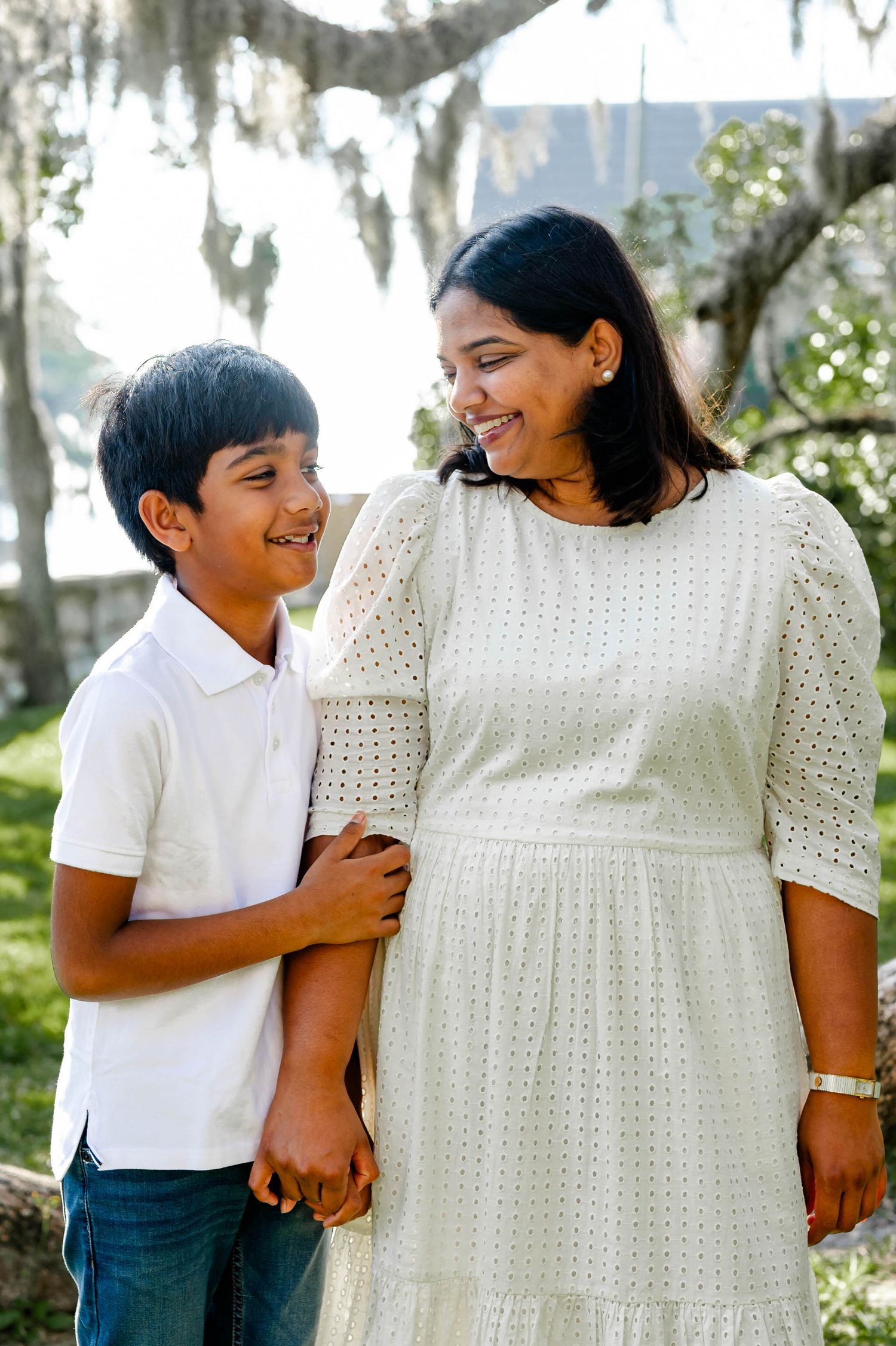 A series of three photos showing a child in white shirt and dark pants embracing someone in a white dress outdoors.