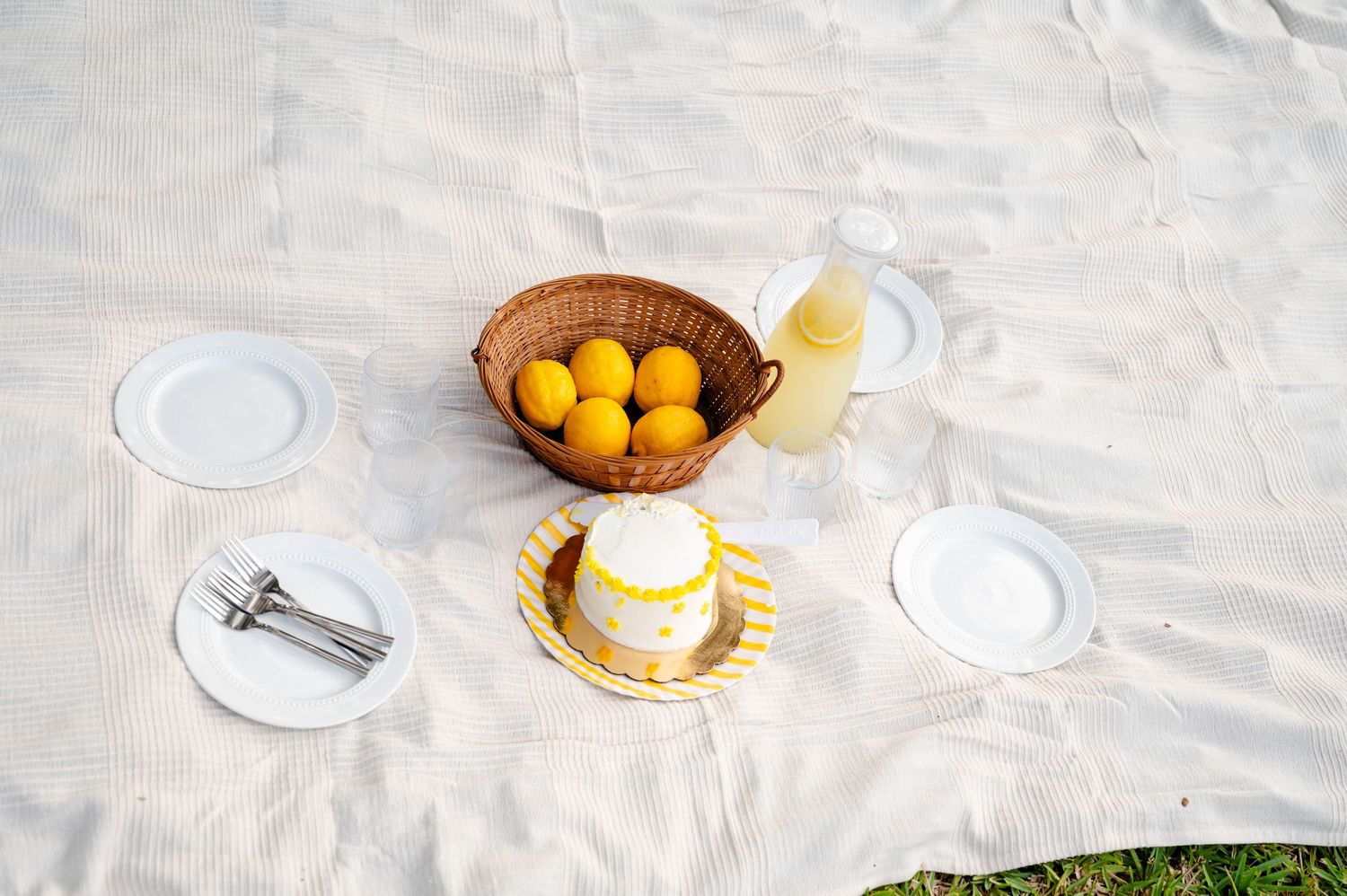 White table setting with fresh lemons and citrus fruits in woven basket.