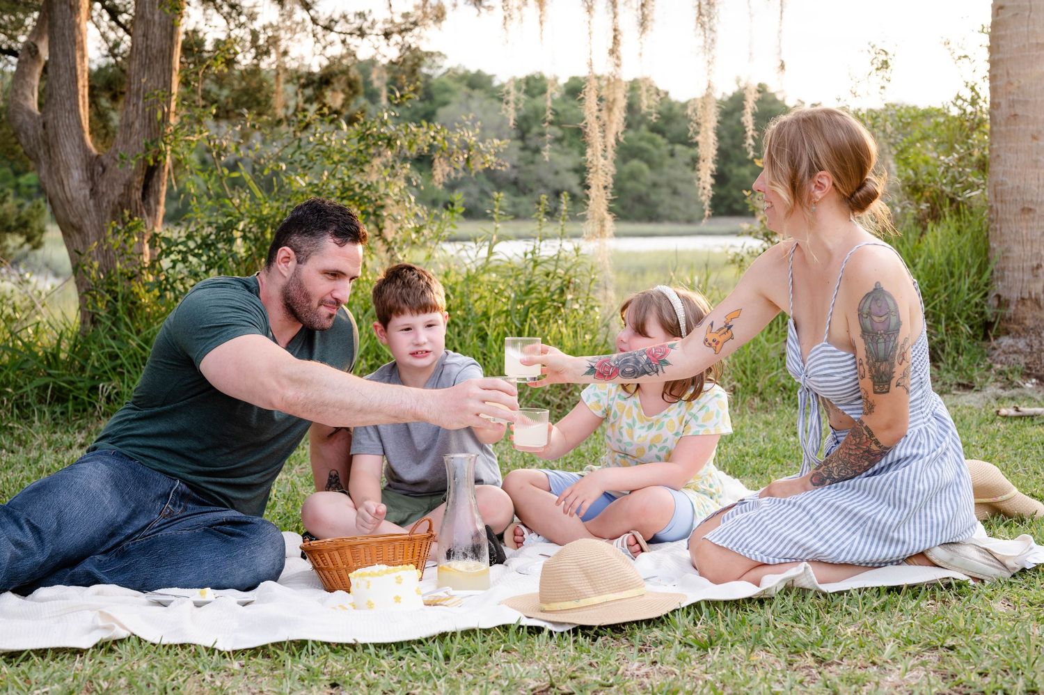 Family enjoying a picnic together on a blanket in a sunny garden setting.