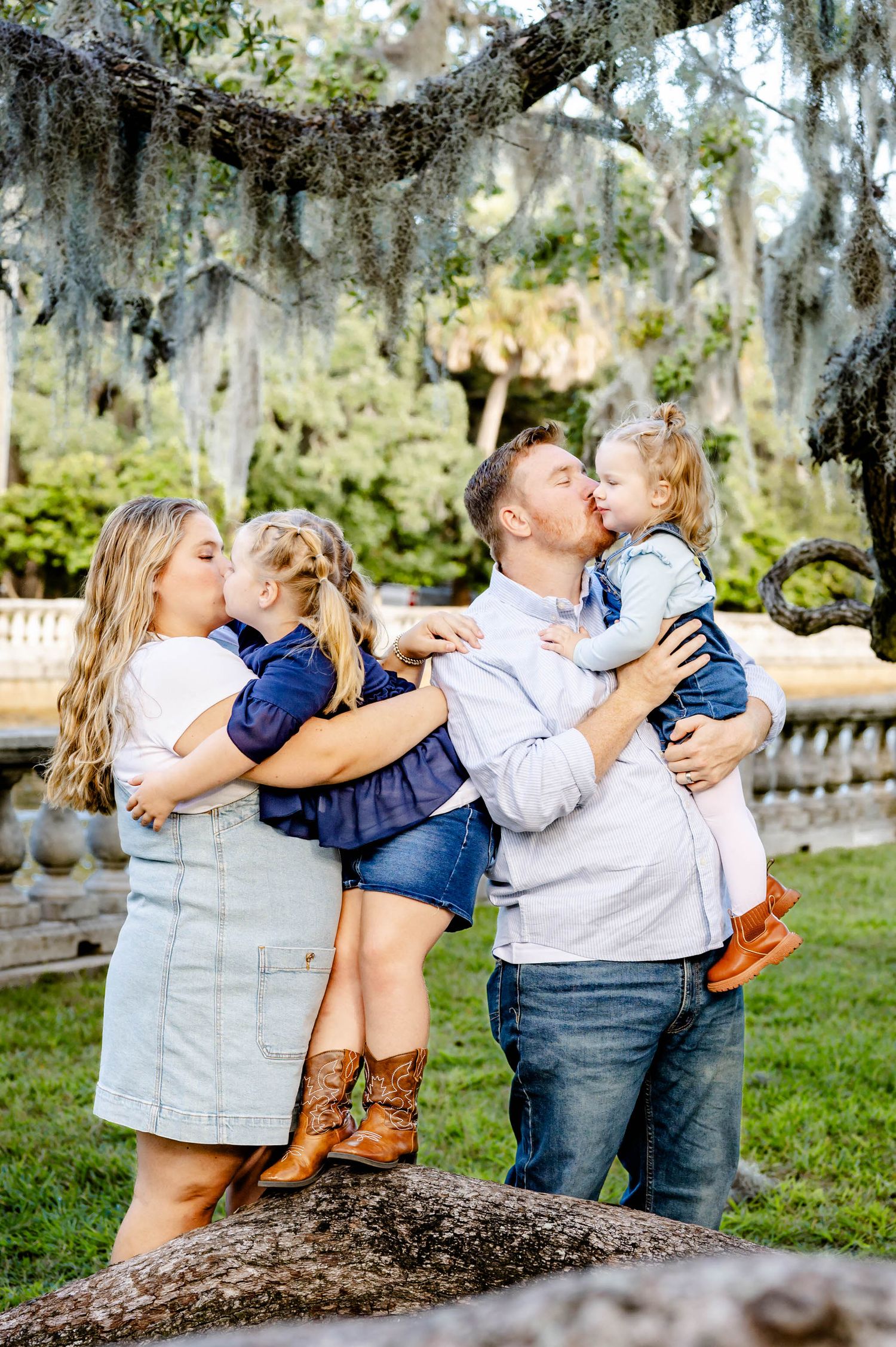 Family shares tender embraces while standing together in a lush garden setting at a spring mini session in jacksonville, fl.