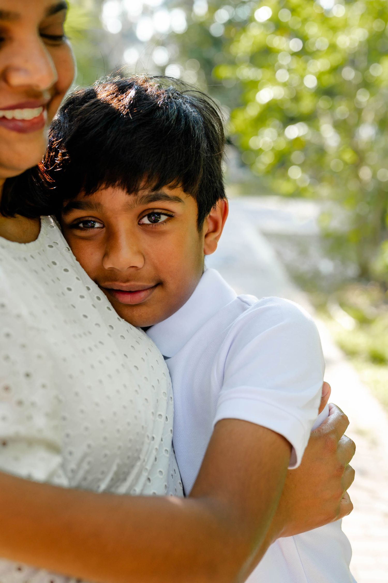 A close-up portrait shows a warm embrace in natural sunlight with bokeh effects in the background.