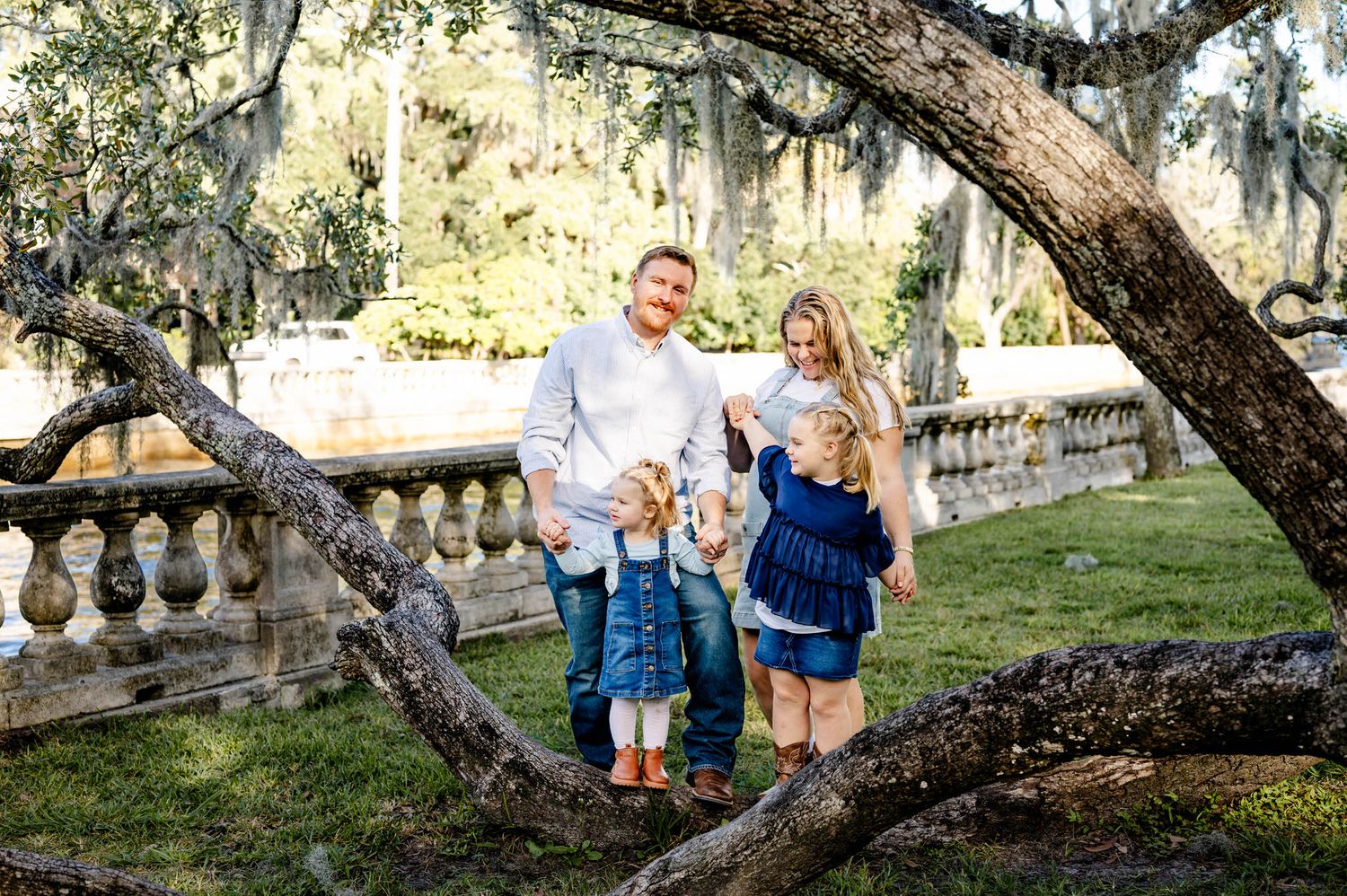 Family photo session in a park with Spanish moss draped oak trees during golden hour lighting at a spring mini session in jacksonville, fl.