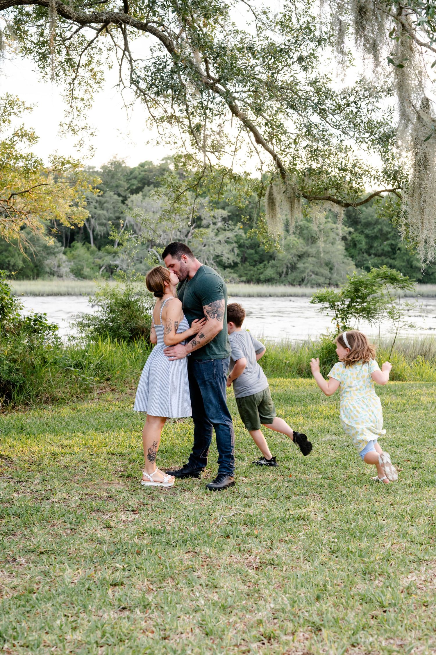 Family playing and having fun together in grassy field by lake.