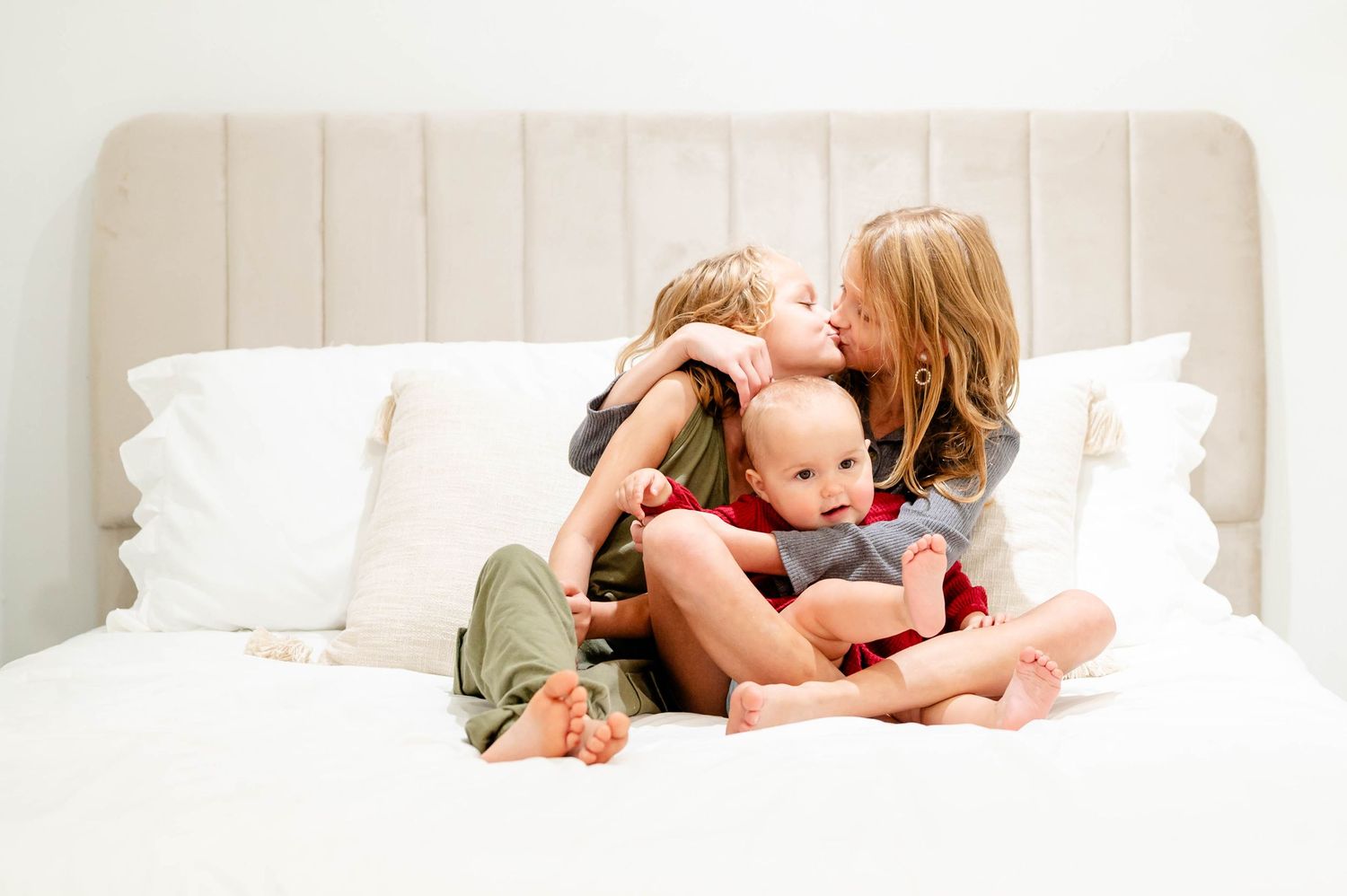 Intimate family moment captured on white bedding during an indoor Jacksonville photography session.