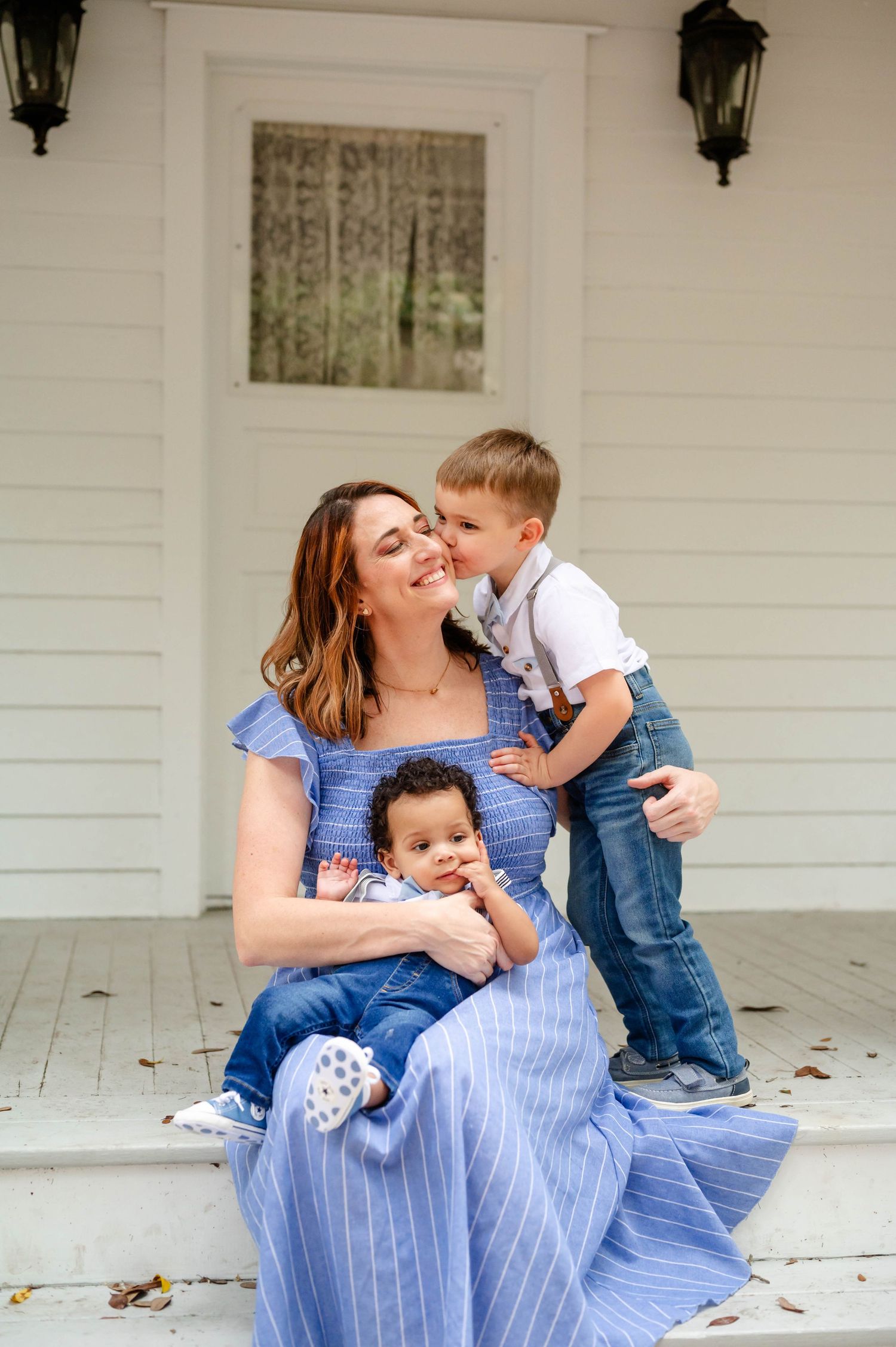 Family enjoying tender moments on front porch wearing coordinated blue and white outfits.
