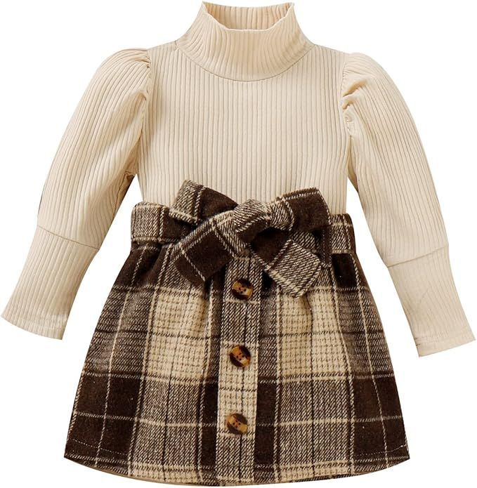 Cream ribbed turtleneck dress with brown plaid skirt and bow belt detail.