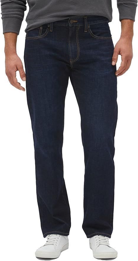 Dark wash straight fit men's jeans styled with white sneakers.
