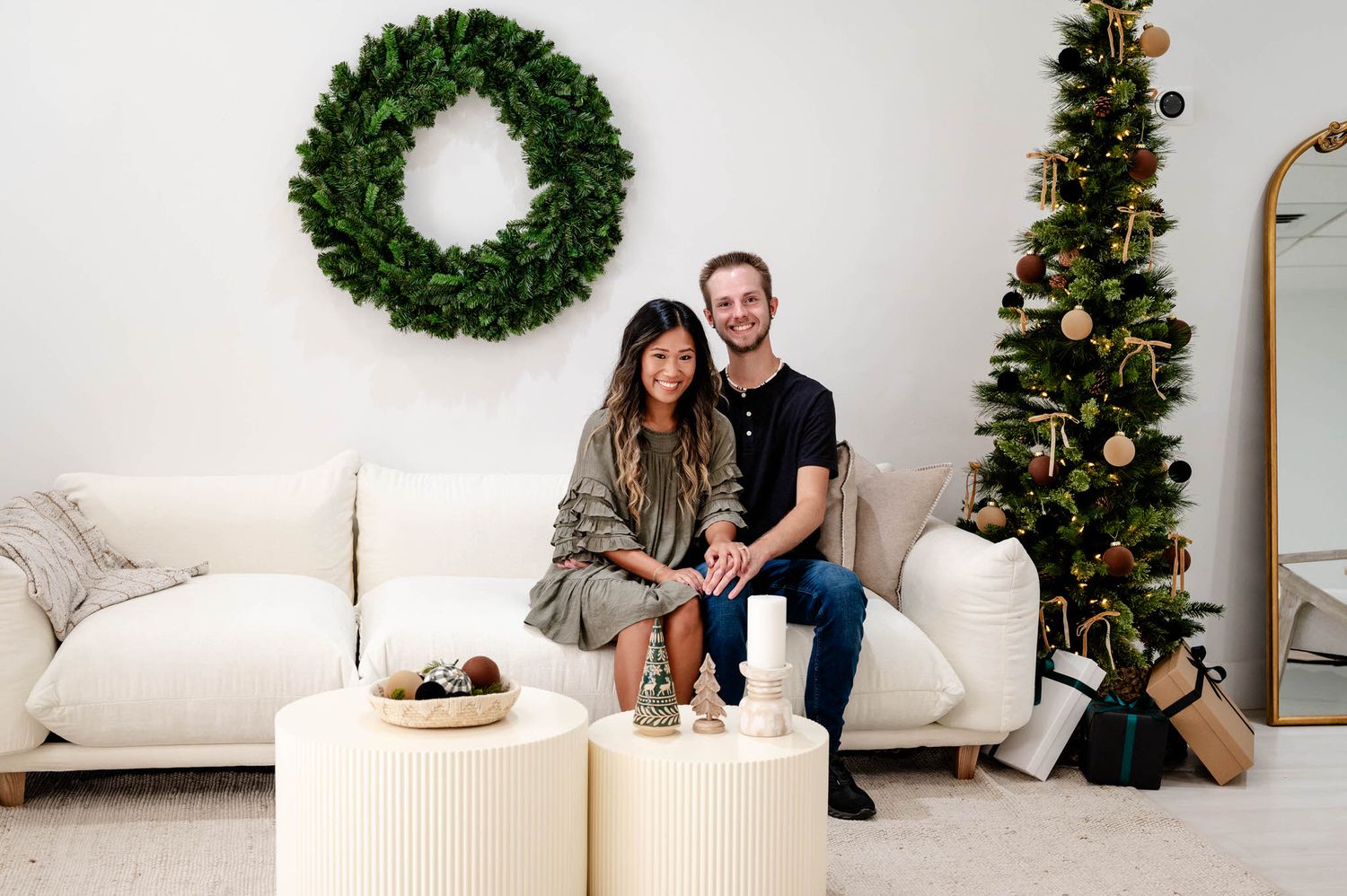 Cozy holiday scene with evergreen wreath and Christmas tree decorations in a minimalist white living room.