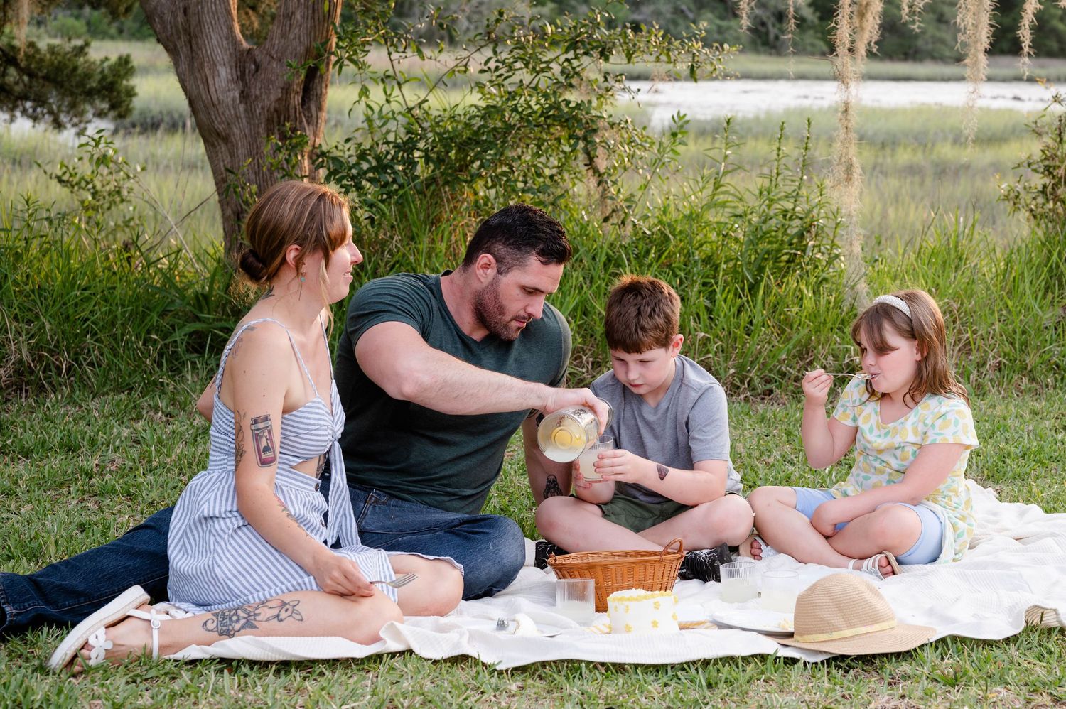 Jacksonville Family sharing snacks together during outdoor picnic photoshoot by the water.
