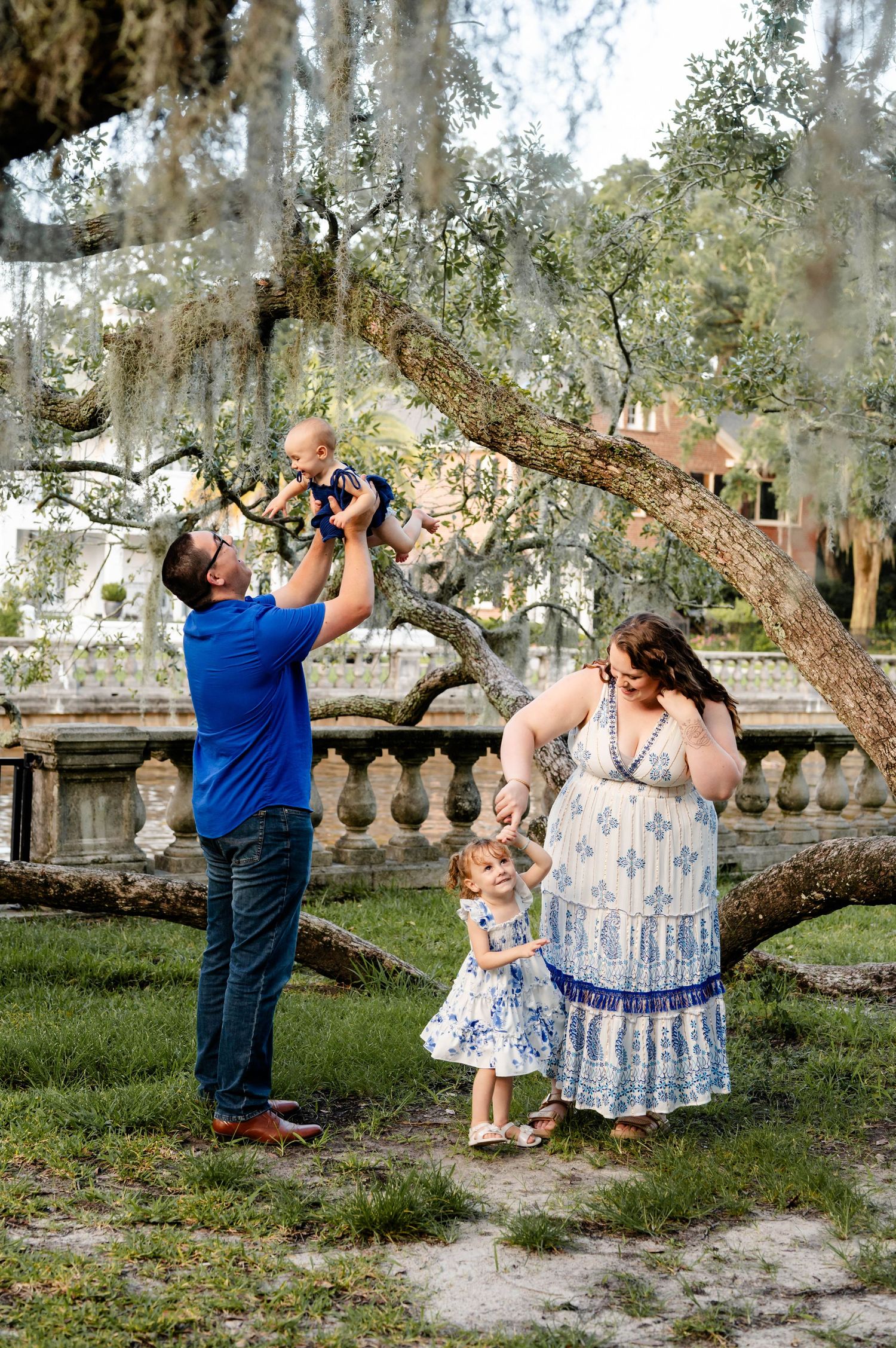 A playful family moment playing under Spanish moss draped trees in a park setting for a spring mini session in jacksonville, FL
