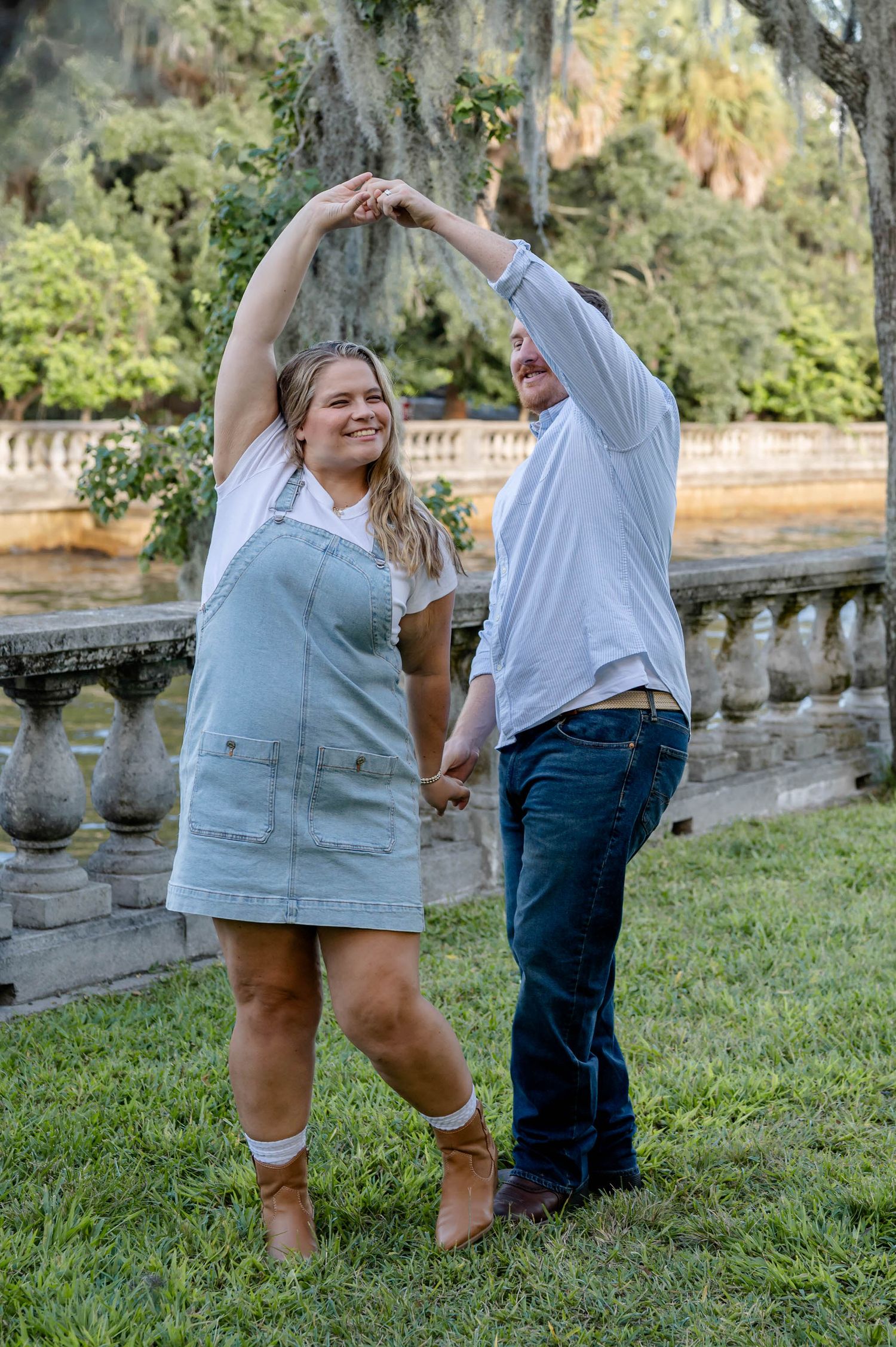 A playful couple dances and laughs together on a grassy lawn with Spanish moss at a spring mini session in jacksonville, fl