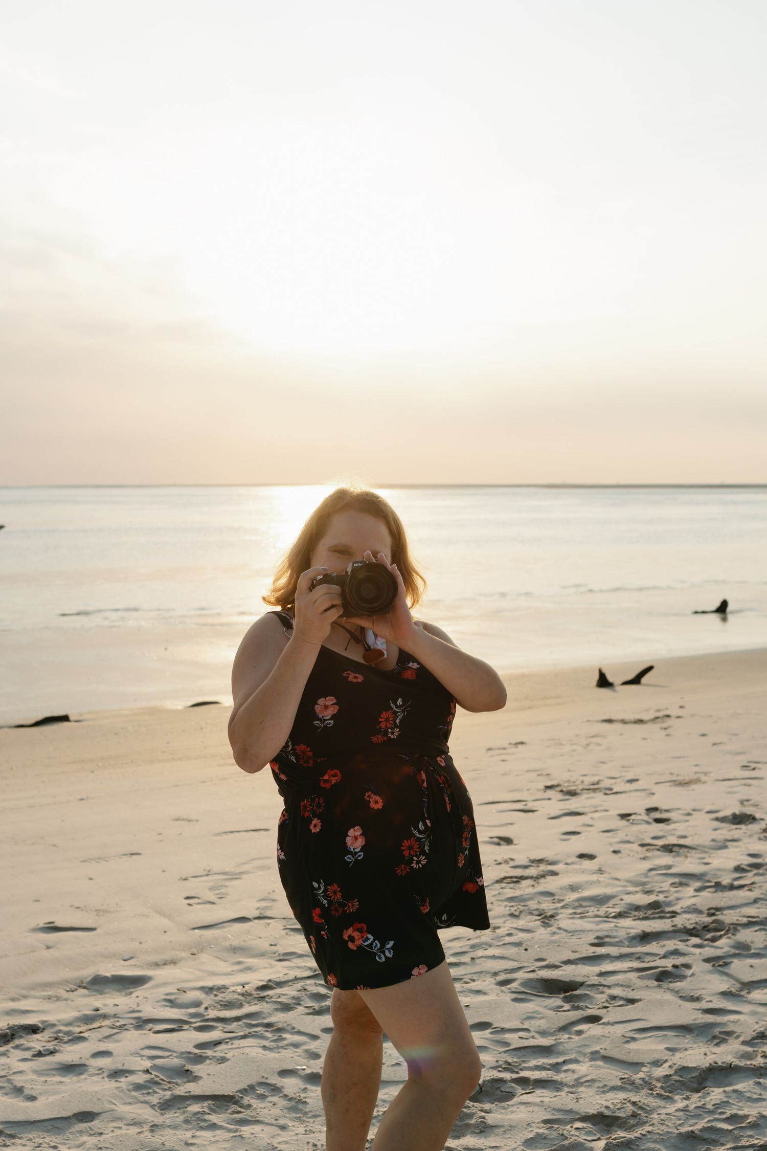 Photographer captures sunset along a peaceful beach with gentle waves and soft sand in fading golden light.