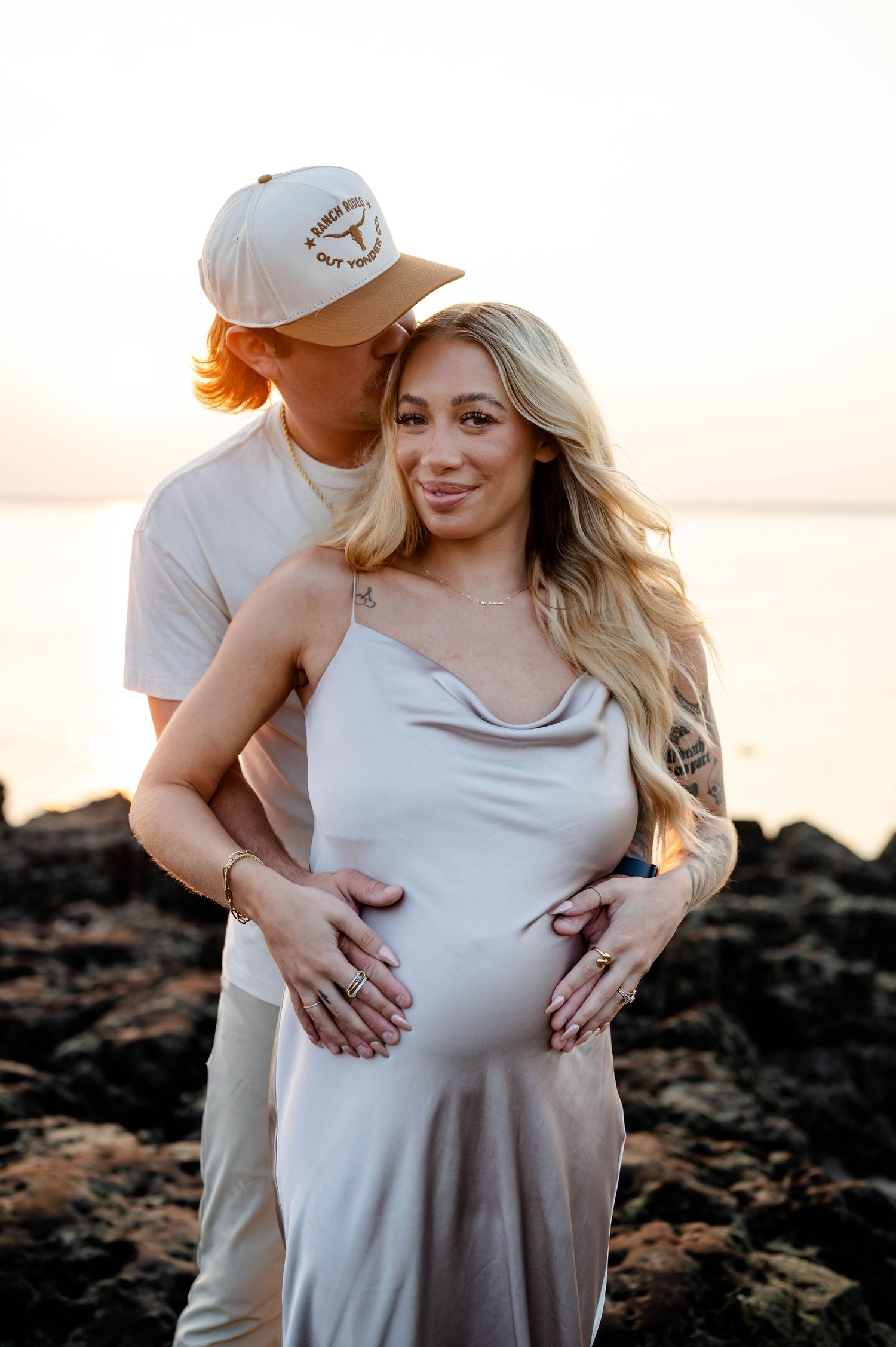 Couple embracing during a Jacksonville sunrise maternity photoshoot on rocky coastline at Black Rock Beach, Jacksonville.