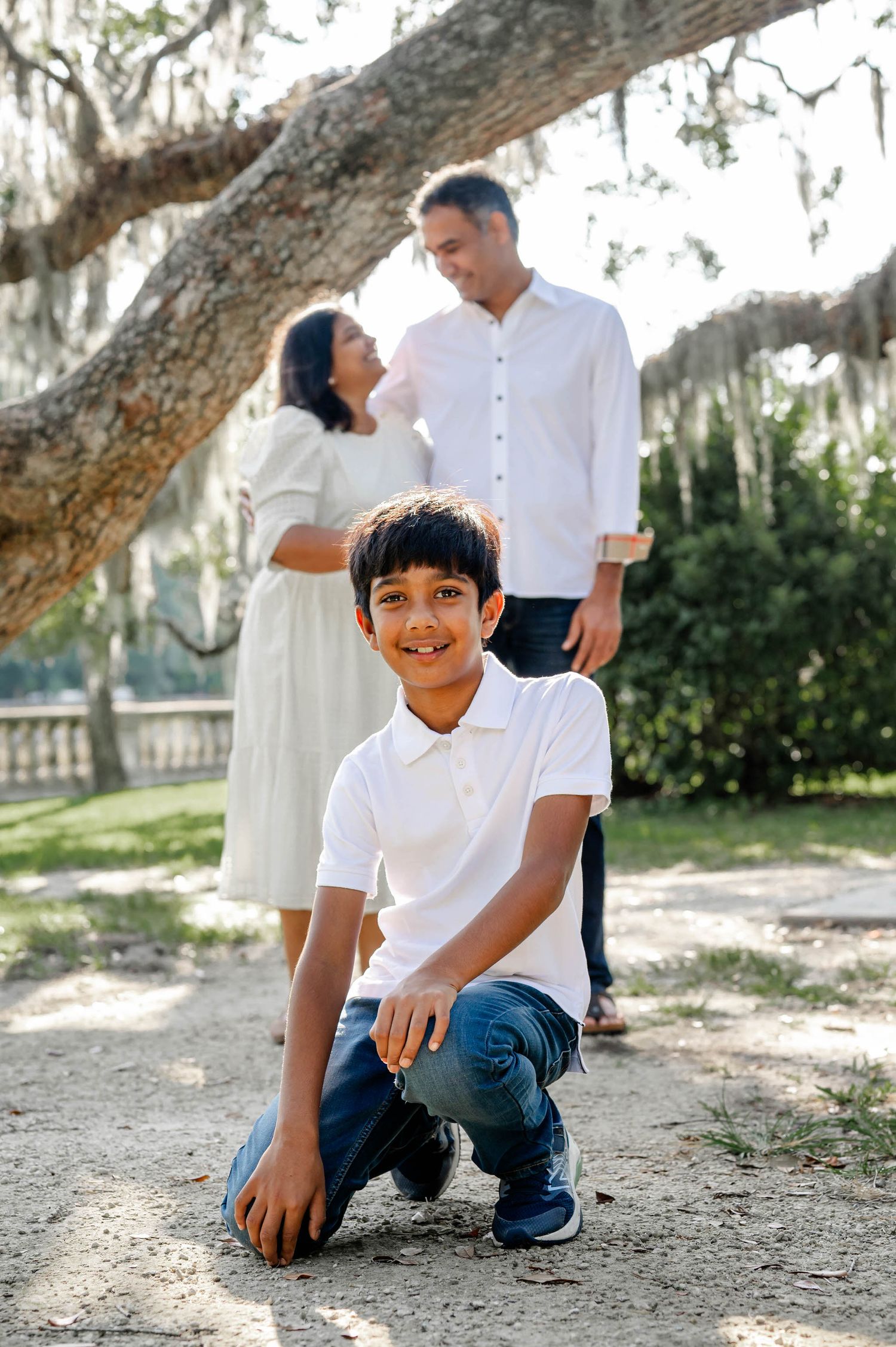 A series of candid outdoor family photos taken under a large oak tree on a sunny day at a spring mini session in jacksonville, fl