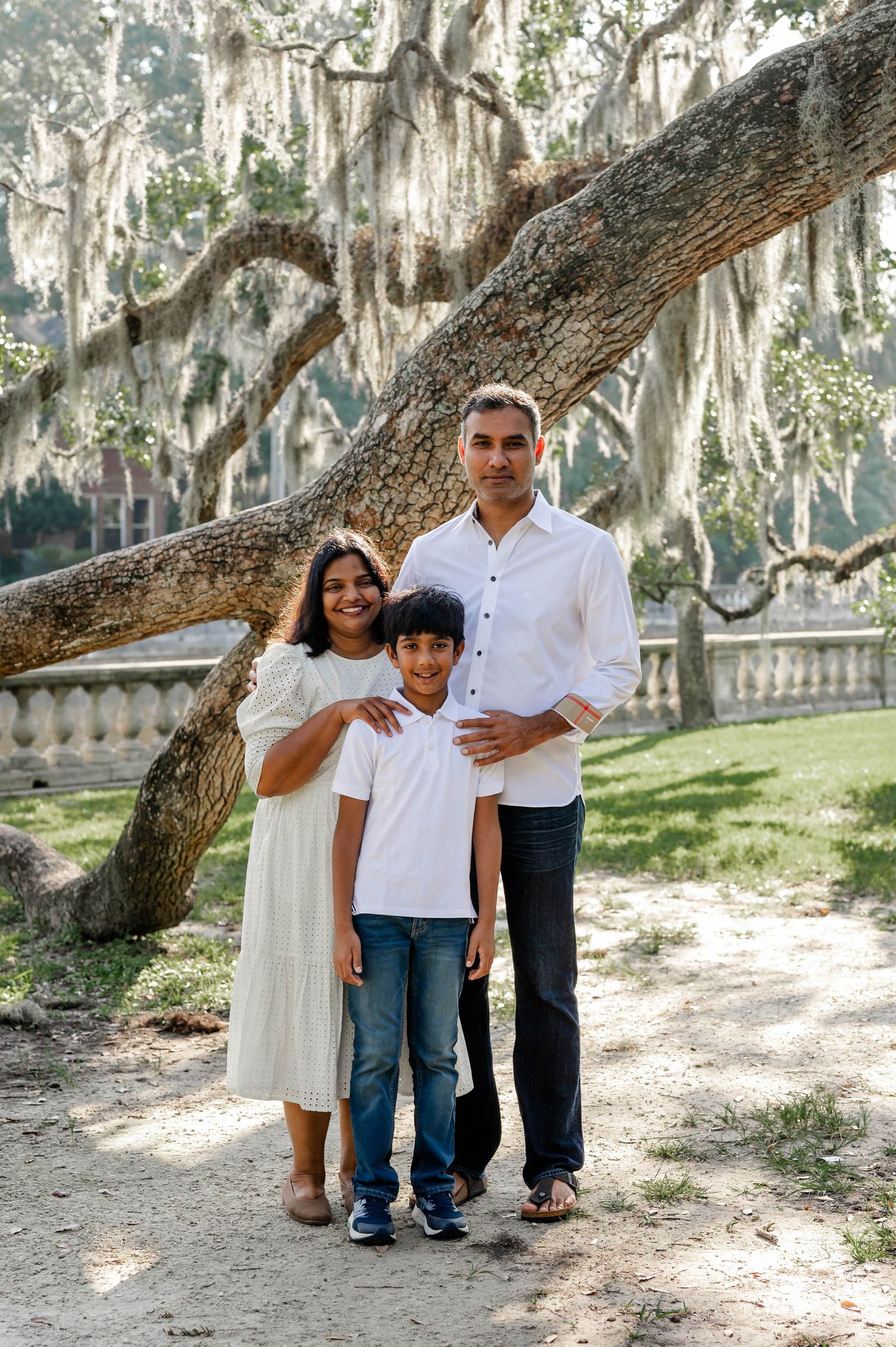 A family poses together under Spanish moss-draped trees in a serene outdoor setting at a spring mini session in jacksonville, fl