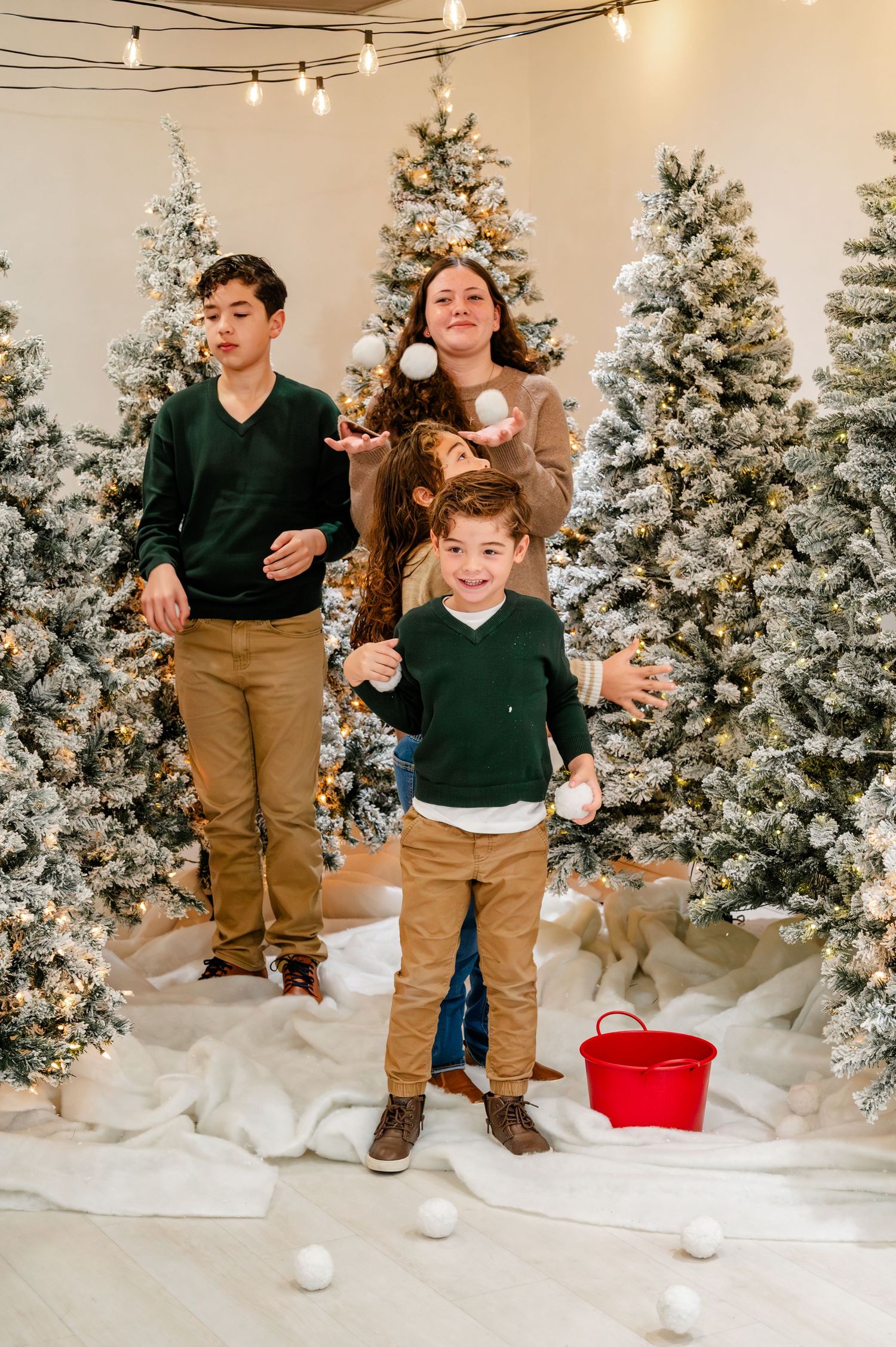 A winter photo sequence showing playful snowball throwing moments against a backdrop of snow-covered Christmas trees and lights.