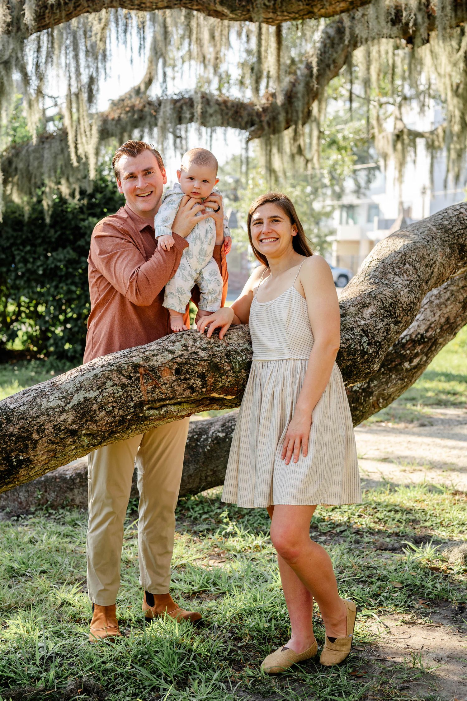 Family poses together under Spanish moss draped oak tree in a Southern garden setting.