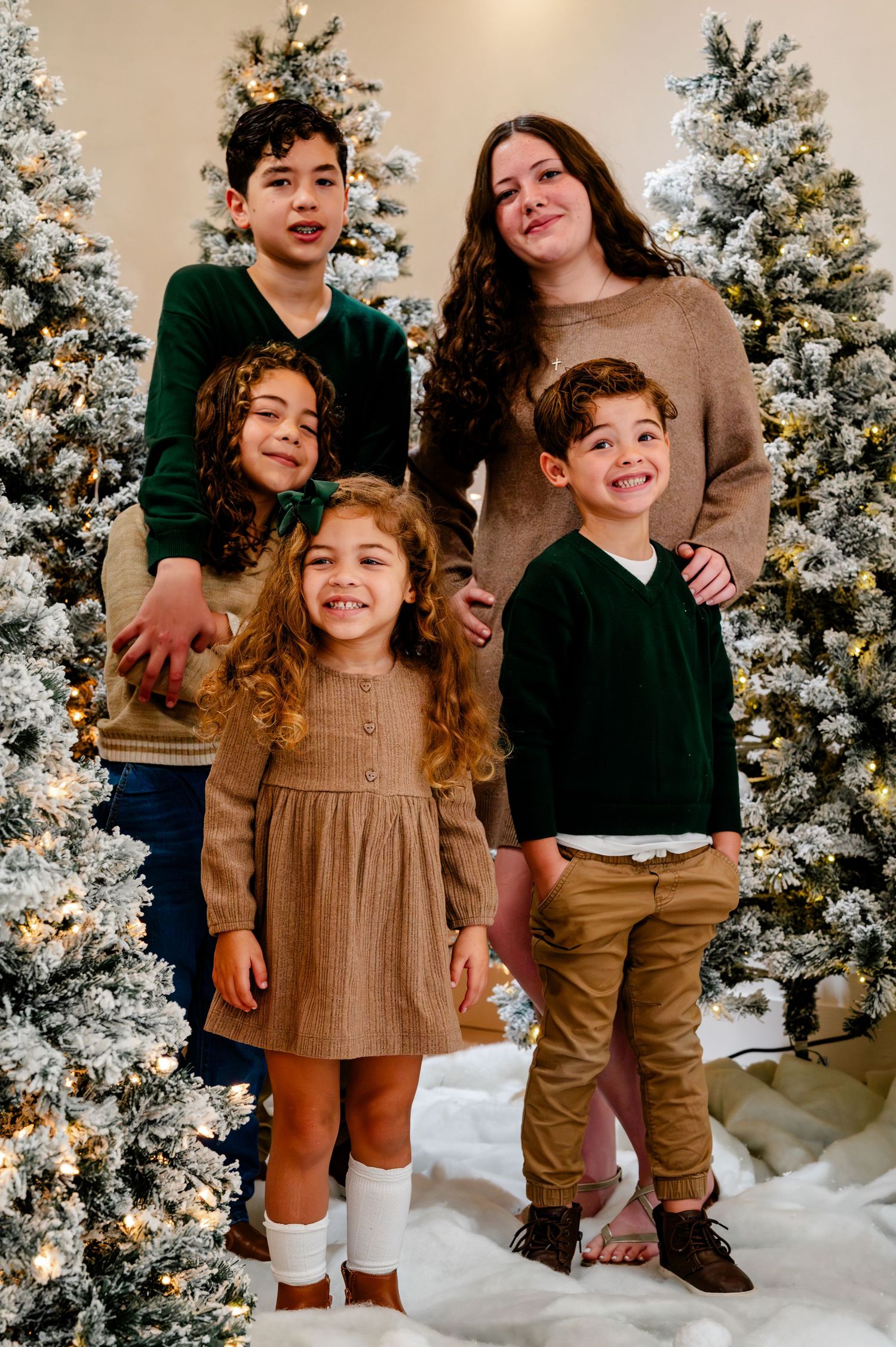 A festive holiday photo session with a snowy backdrop and decorated Christmas trees.