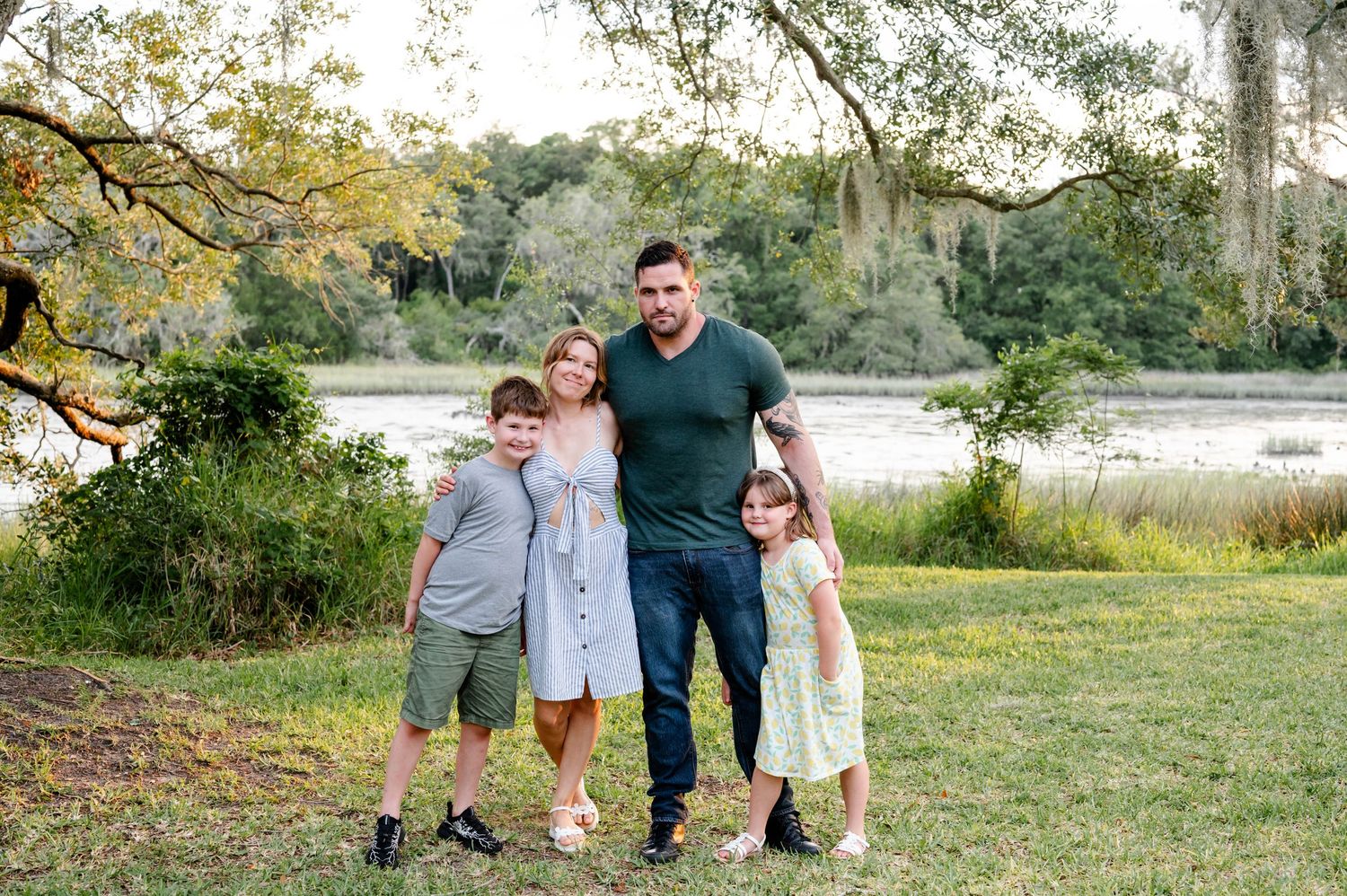 Family group photo posing together on grassy area near a waterfront Jacksonville park.