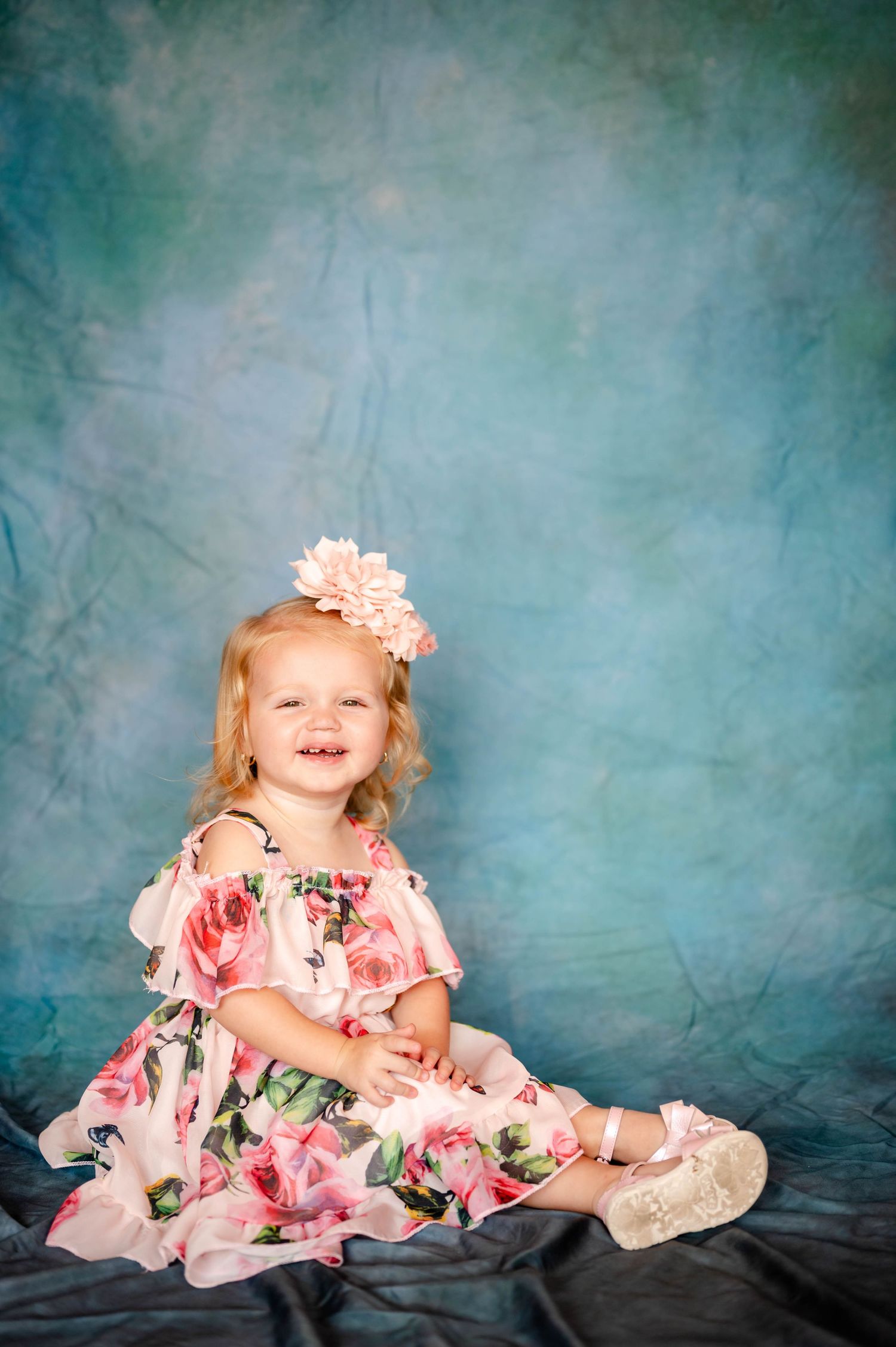 Child in pink floral dress posing against teal backdrop during school photos in Jacksonville.