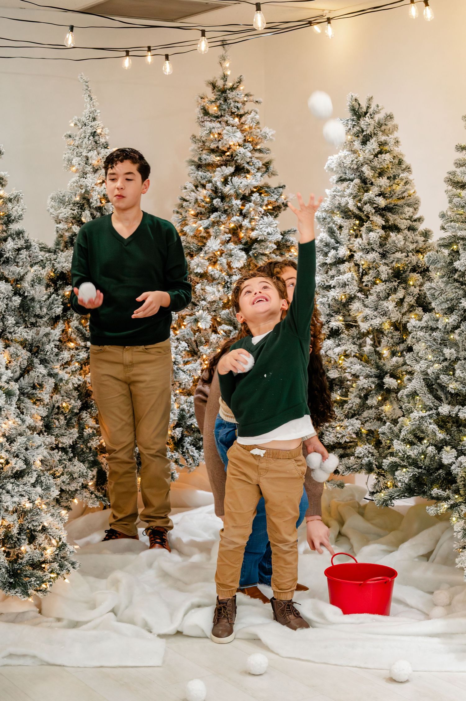 Indoor snowball fight scene with decorated Christmas trees in background and person tossing white snowballs.